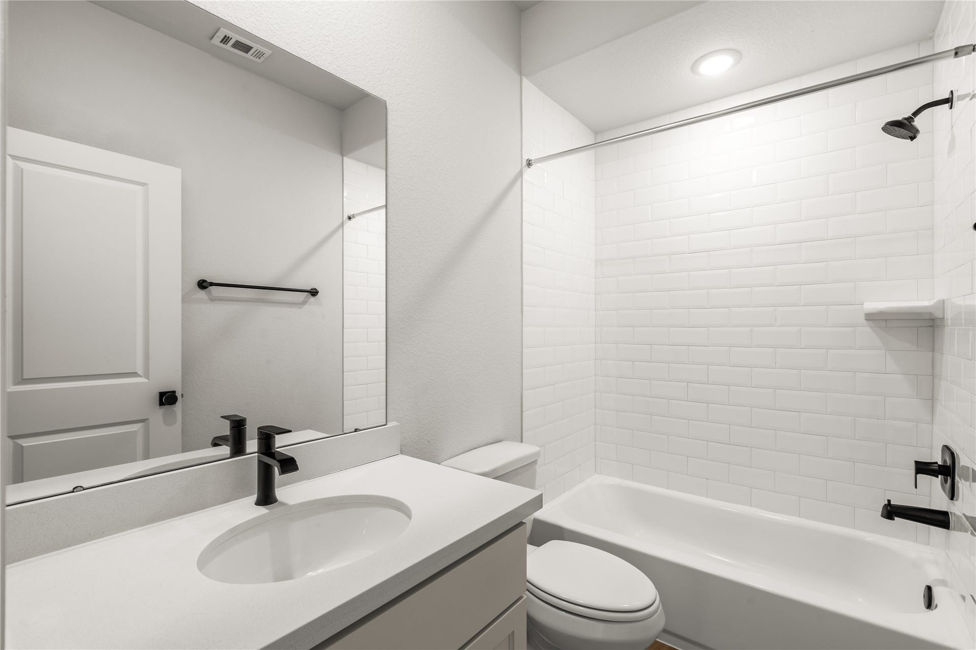 9607 Maple Wood Drive, Missouri City, TX 77459 Secondary bathroom featuring a modern vanity with a black faucet and a pristine white subway tile shower with matching black fixtures.