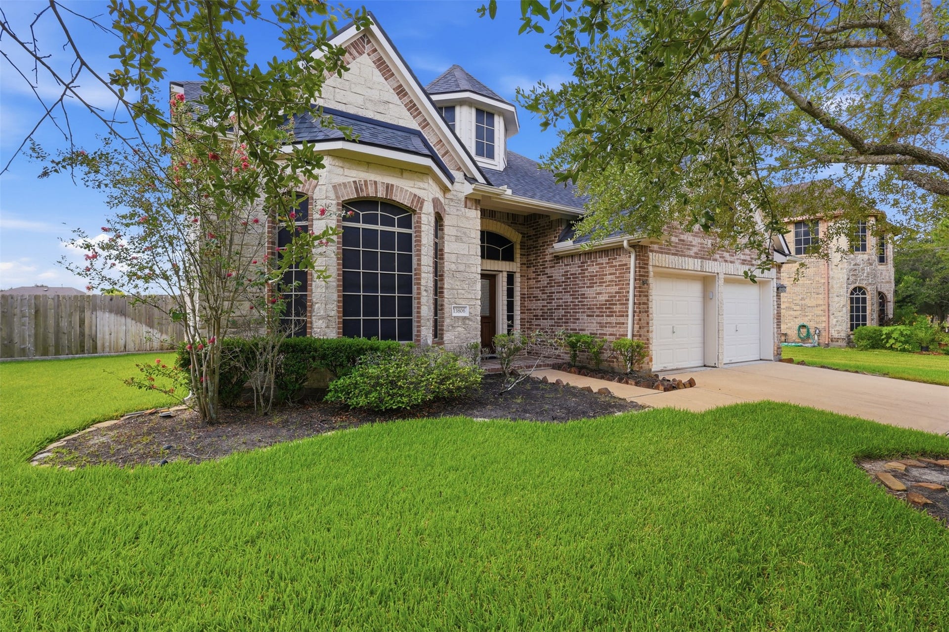 13806 Cove Landing Lane, Rosharon, TX 77583 Stone and brick detailing, dramatic arched windows, and mature landscaping create a distinctive and polished front exterior.