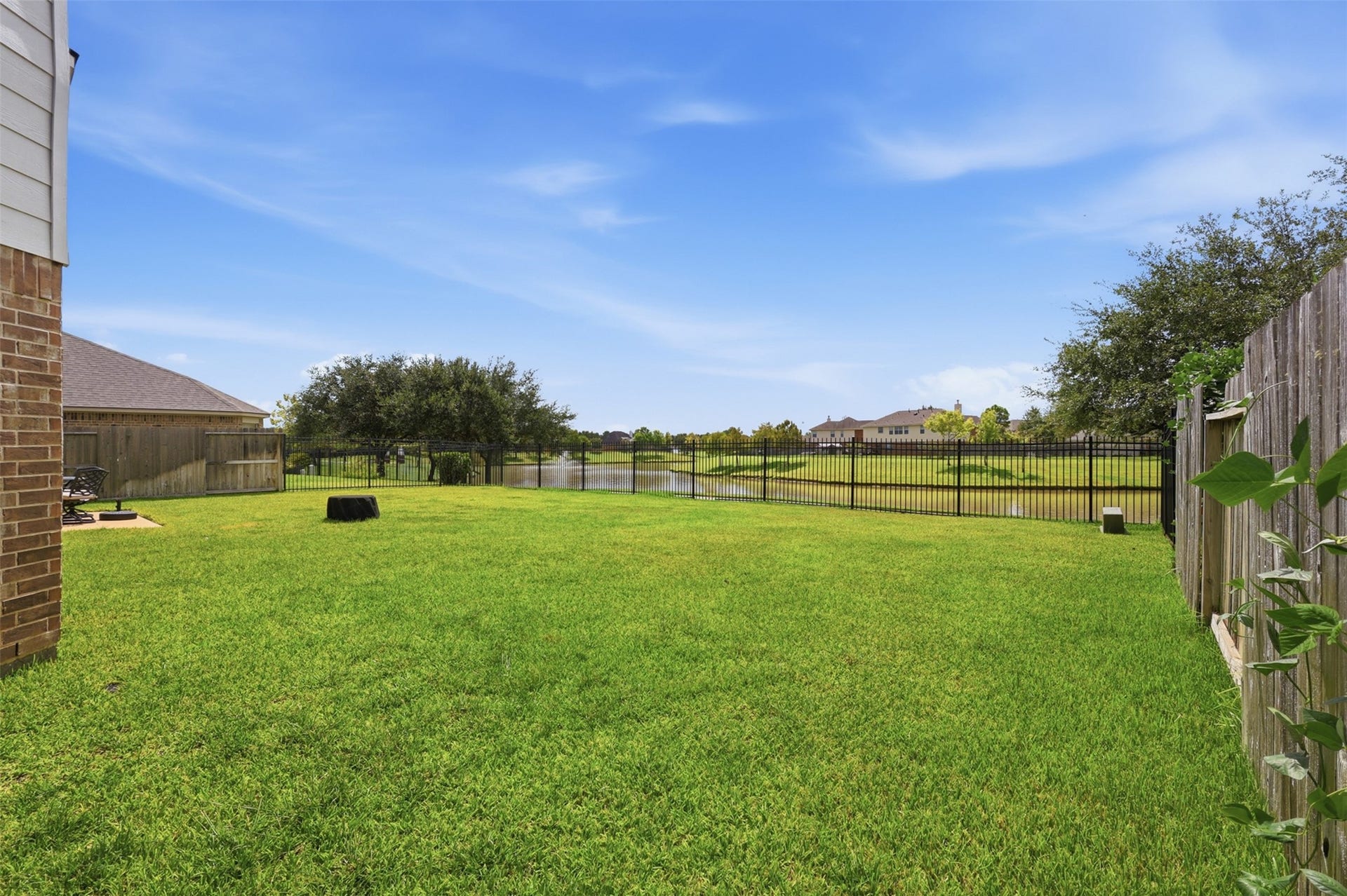 13806 Cove Landing Lane, Rosharon, TX 77583 The expansive fenced backyard enjoys open green space with peaceful views toward the neighborhood lake.