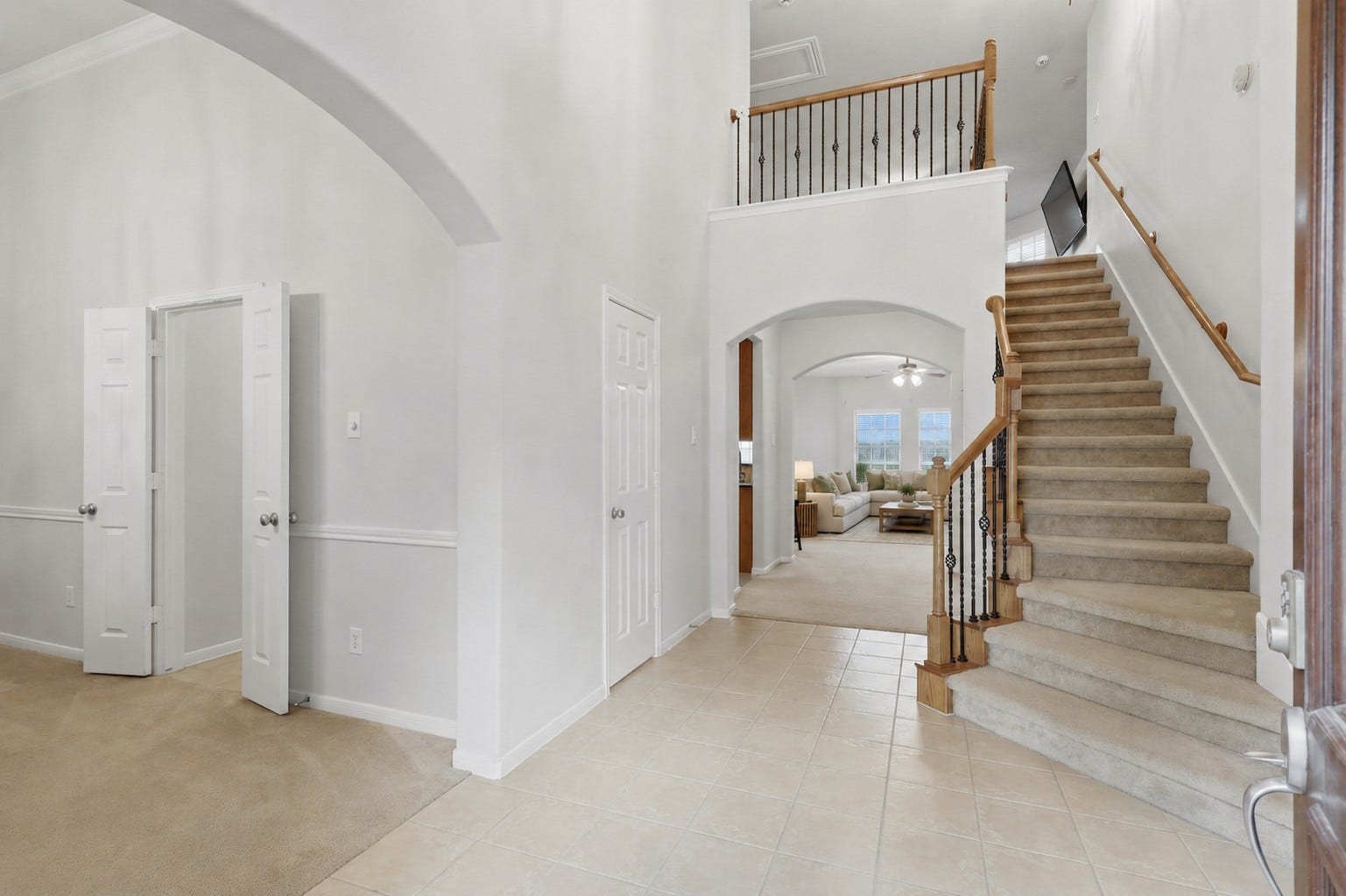 13806 Cove Landing Lane, Rosharon, TX 77583 The soaring entryway features an open staircase, tile flooring, and graceful archways connecting the homes main living spaces.