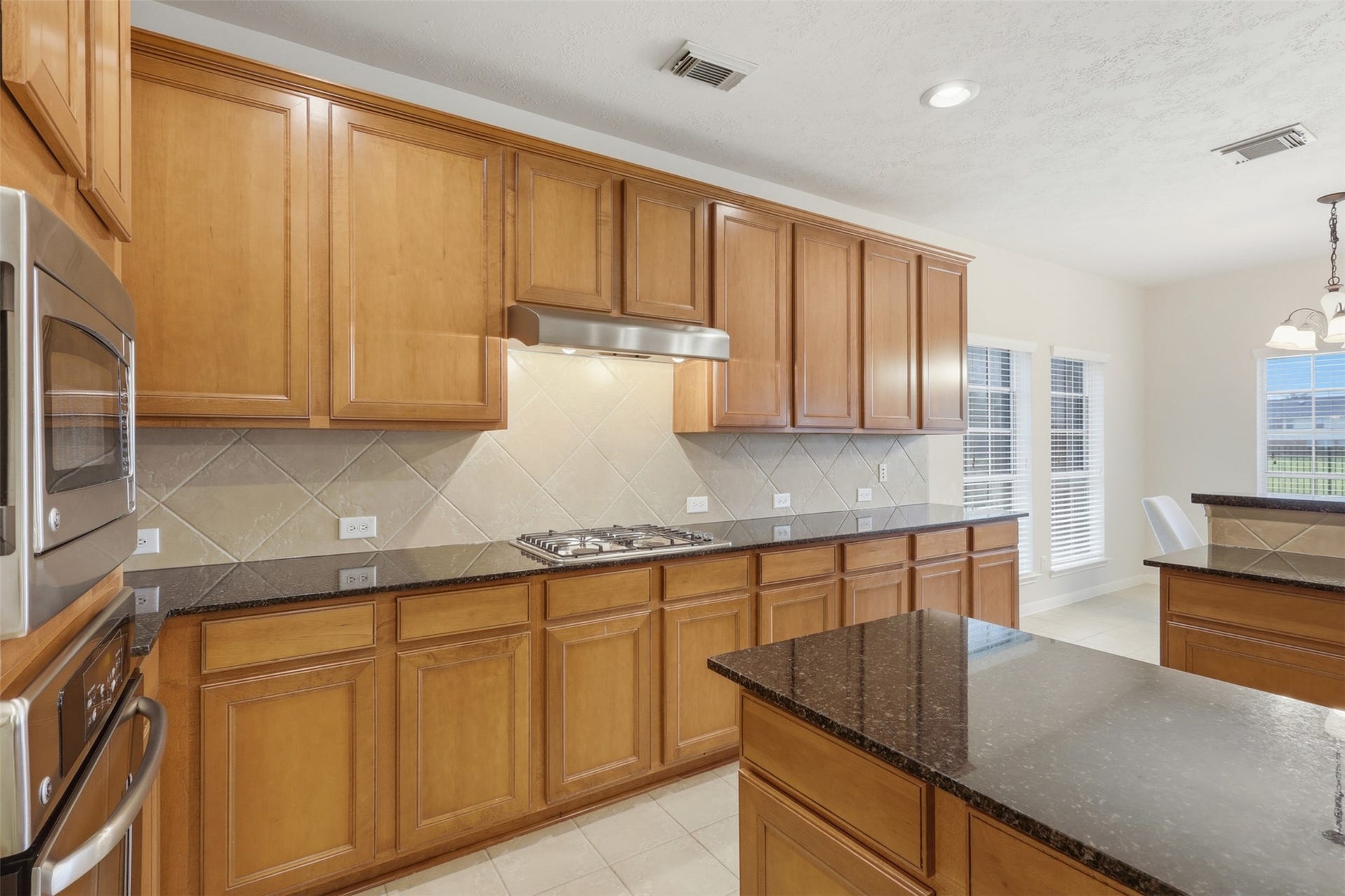 13806 Cove Landing Lane, Rosharon, TX 77583 Extensive cabinetry, granite counters, a tile backsplash, and built-in cooking features provide excellent kitchen workspace and storage.