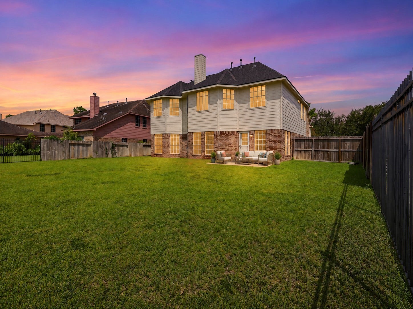 13806 Cove Landing Lane, Rosharon, TX 77583 Twilight views highlight the homes rear elevation, expansive yard, and warm exterior lighting.**Virtually staged