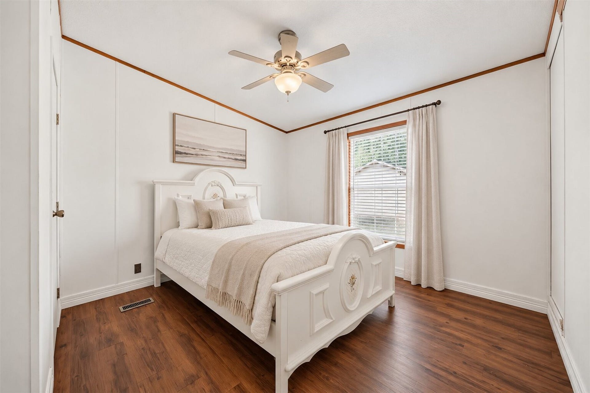 Virtually staged bedroom with natural light, ceiling fan, and wood look flooring.
