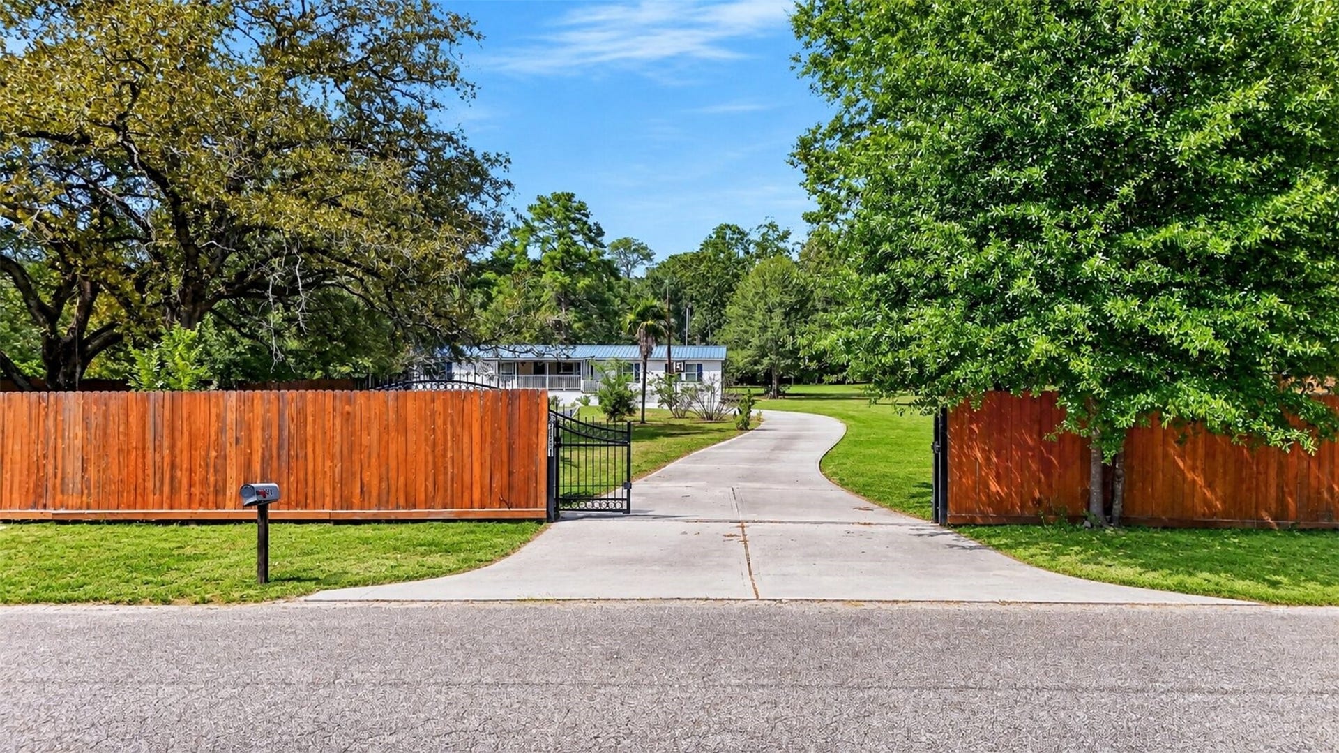 Another view of the gated entrance and extended driveway leading toward the home.