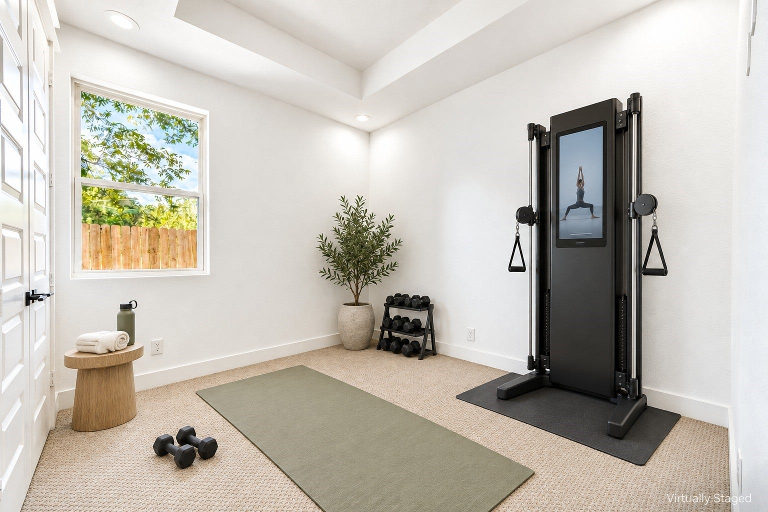 Versatile first-floor space configured as a home gym, featuring a clean tray ceiling, neutral textured carpeting, and a window overlooking the backyard. *virtually staged