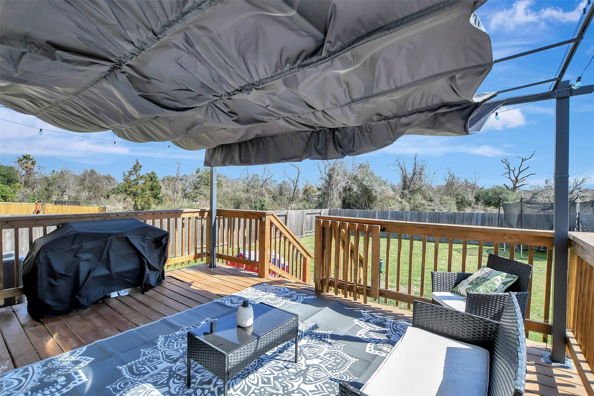 Backyard retreat featuring a large deck with covered awning  perfect for relaxing evenings or entertaining guests.