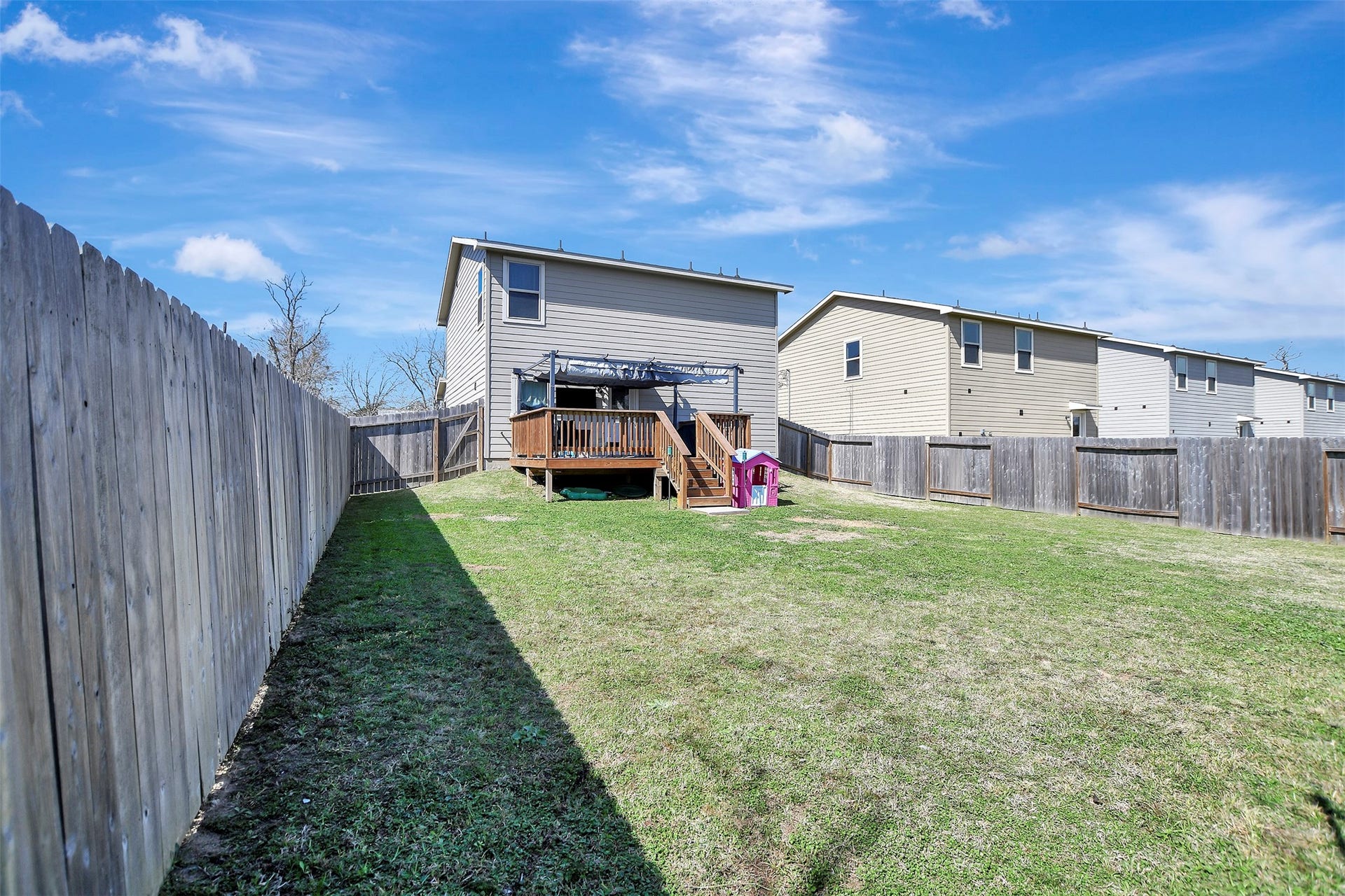 Privacy-fenced backyard situated on the first of two lots, offering secure space for pets, play, or outdoor enjoyment.
