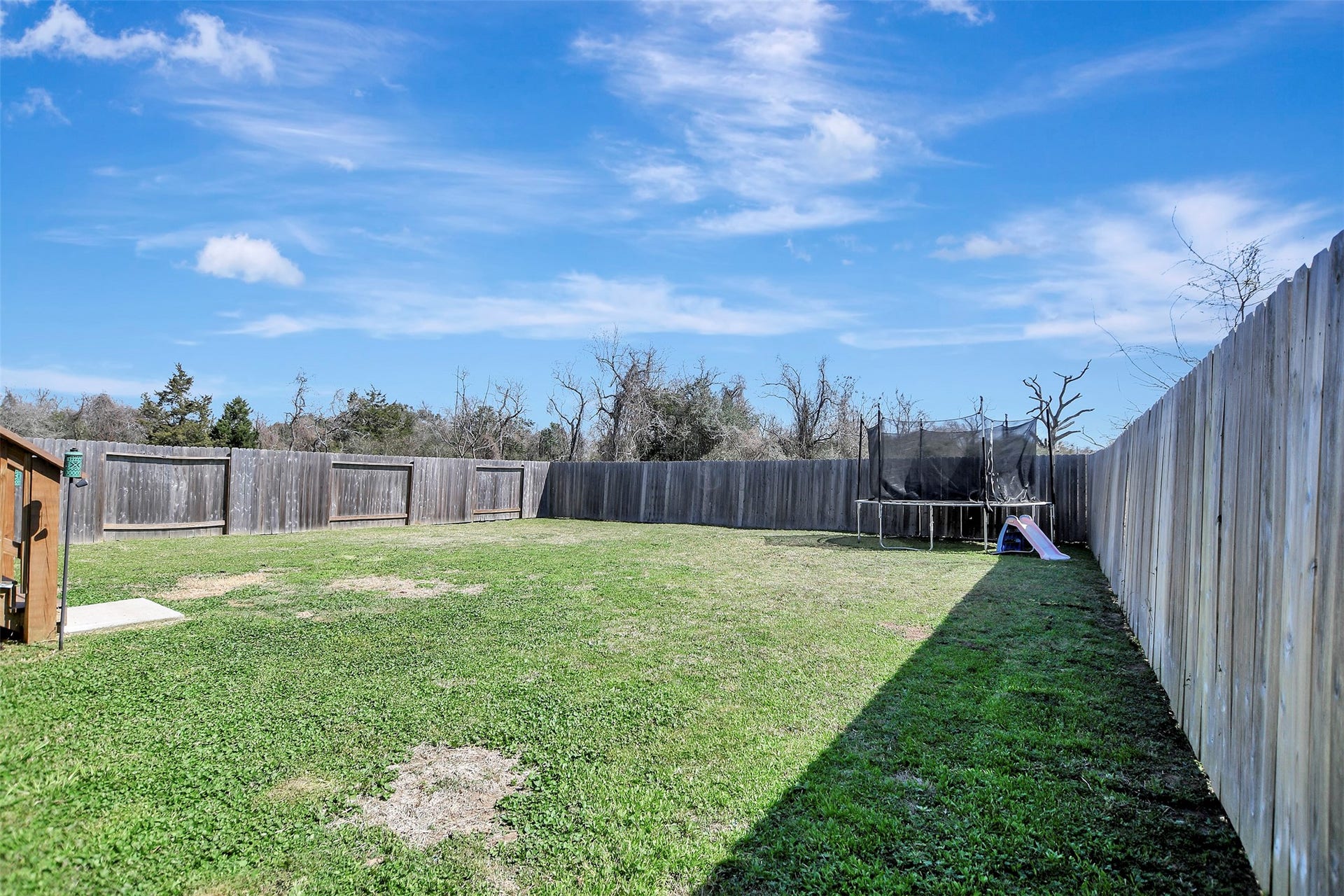 Privacy-fenced backyard situated on the first of two lots, offering secure space for pets, play, or outdoor enjoyment.