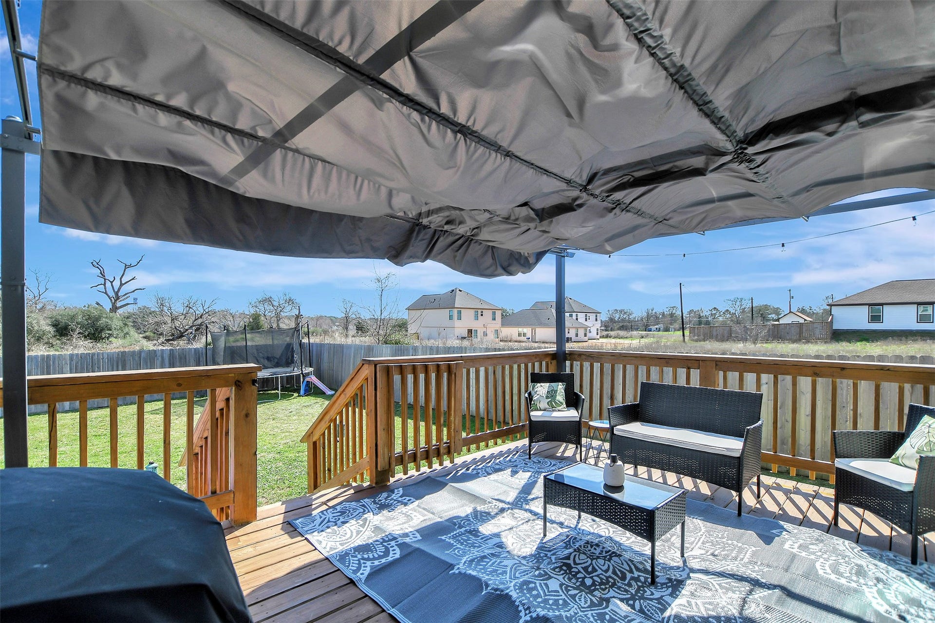 Backyard retreat featuring a large deck with covered awning  perfect for relaxing evenings or entertaining guests.