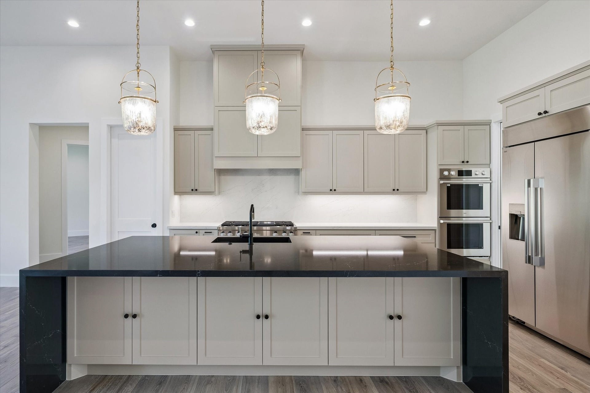 65 Shadow Creek Ridge Drive, Spring, TX 77389 In the kitchen, a dramatic oversized island anchors the space with sleek, dark quartz-style countertops and generous storage below, ready for everything from weeknight meals to weekend grazing boards.