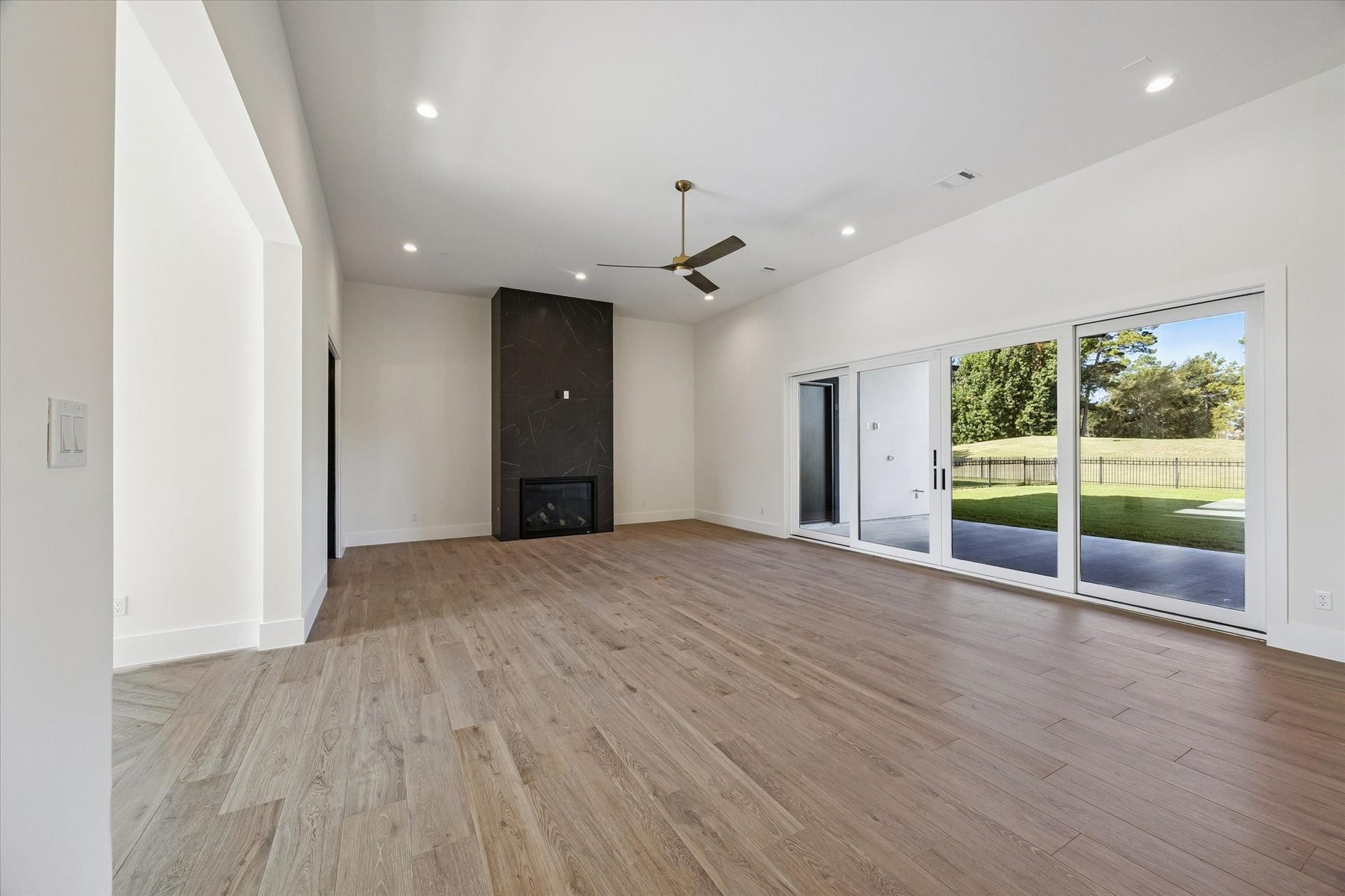 65 Shadow Creek Ridge Drive, Spring, TX 77389 Sunlit living room with wide-plank wood-style tile, sleek fireplace surround, and expansive sliding doors.