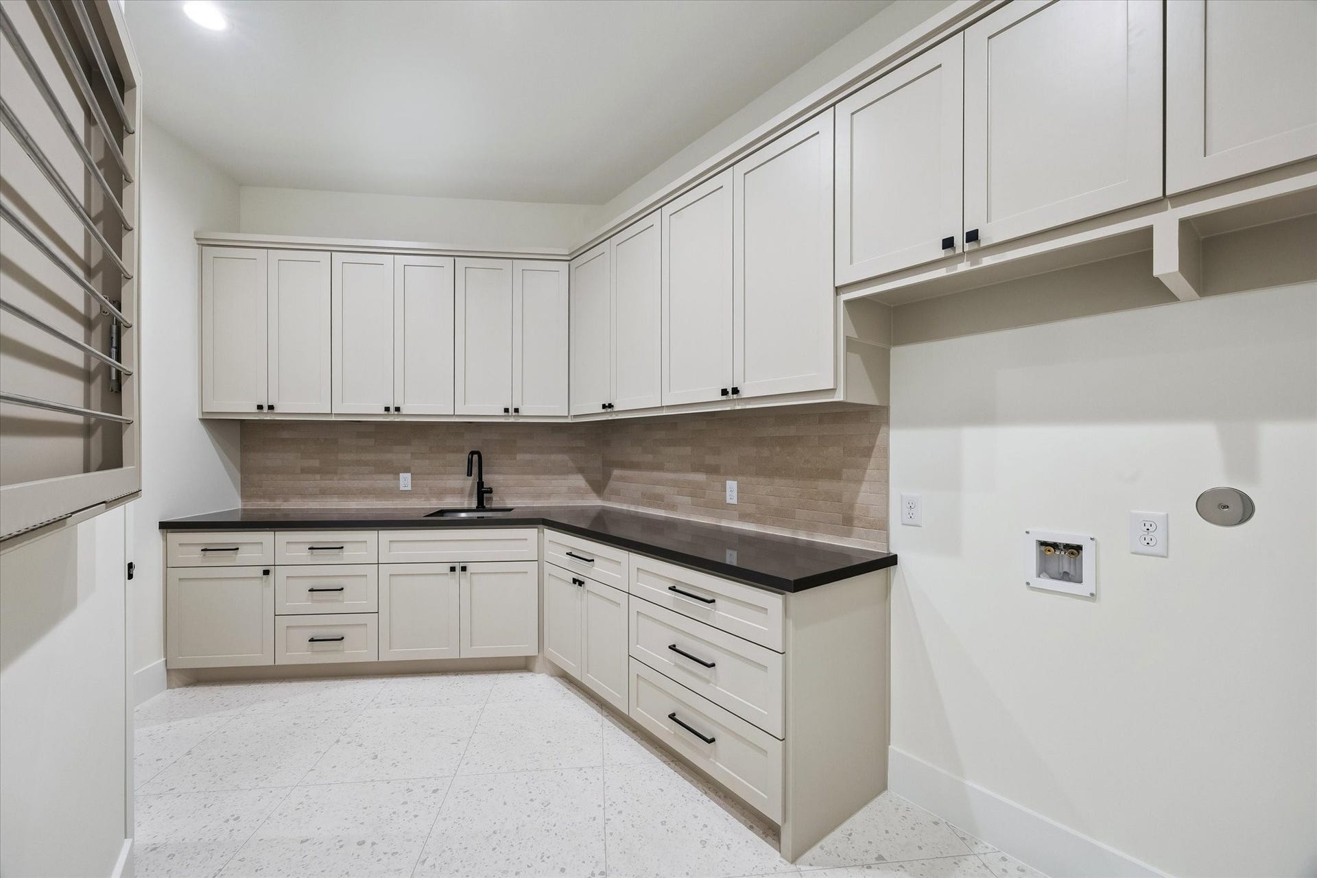 65 Shadow Creek Ridge Drive, Spring, TX 77389 Spacious utility room with custom cabinetry, stone-look counters, and a sleek tile backsplash.