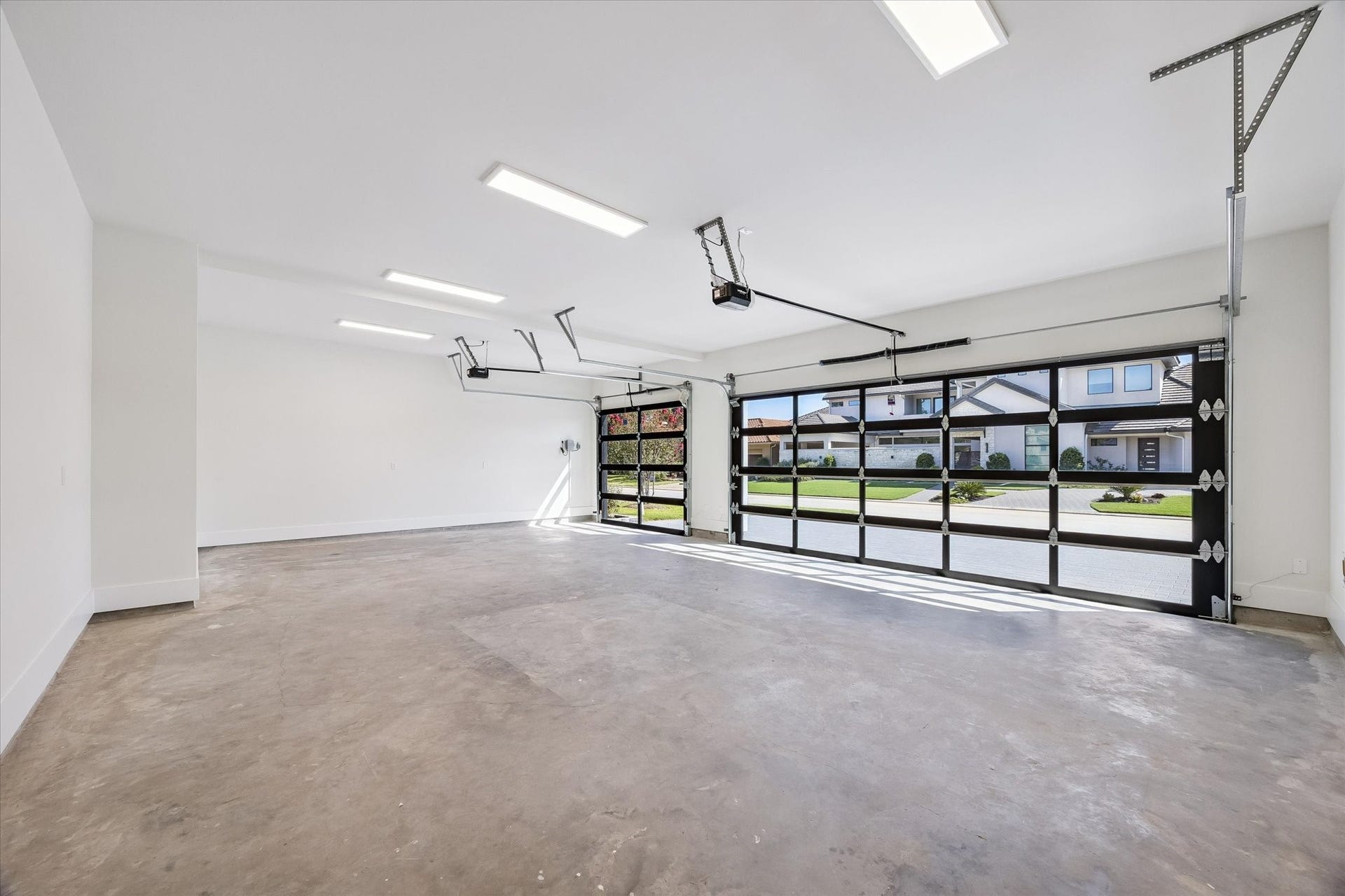 65 Shadow Creek Ridge Drive, Spring, TX 77389 Spacious three-car garage with epoxy-ready floors, bright LED lighting, and sleek glass-panel doors.