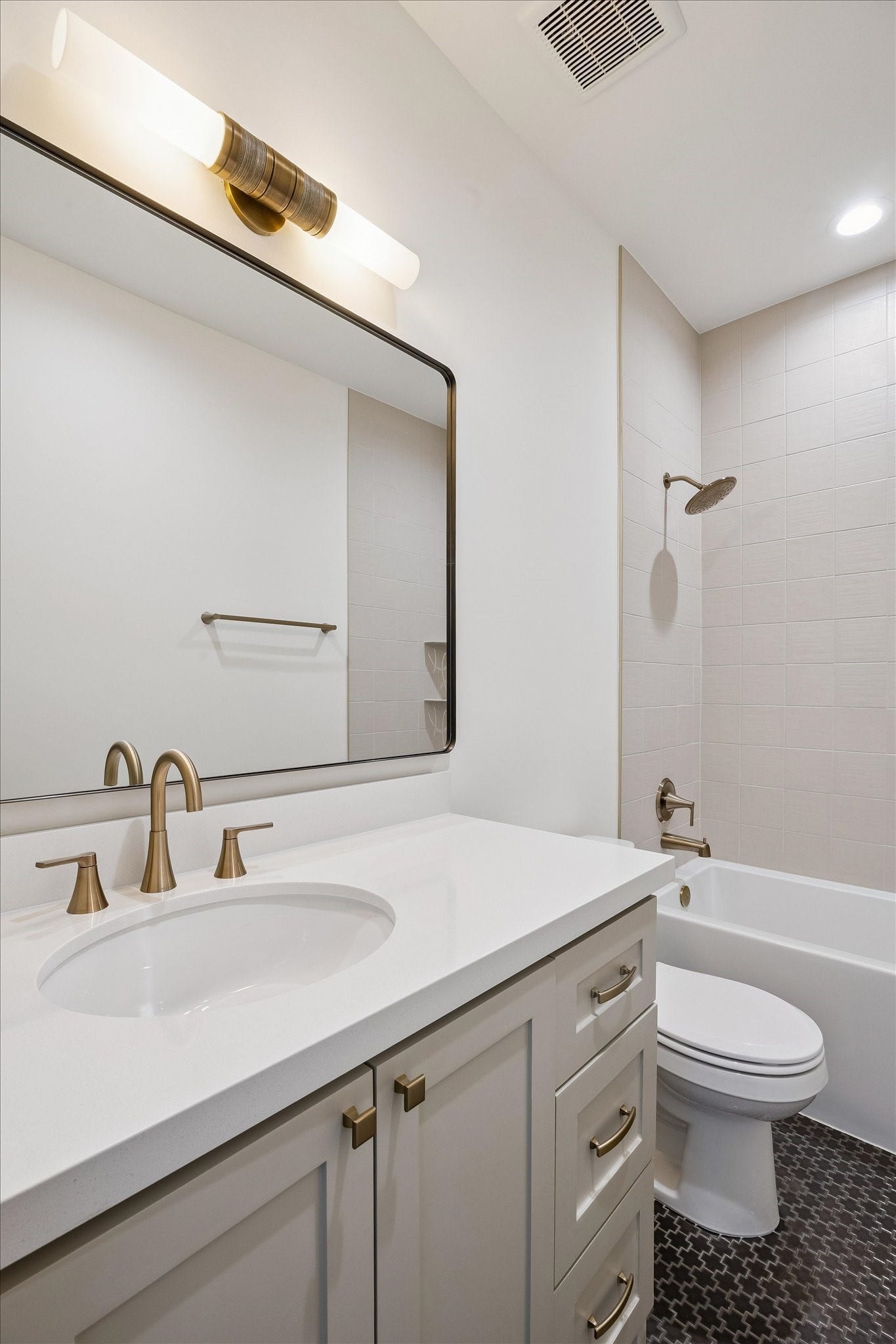 65 Shadow Creek Ridge Drive, Spring, TX 77389 Crisp bathroom with quartz vanity, brushed brass fixtures, oversized mirror, and tiled tub surround.
