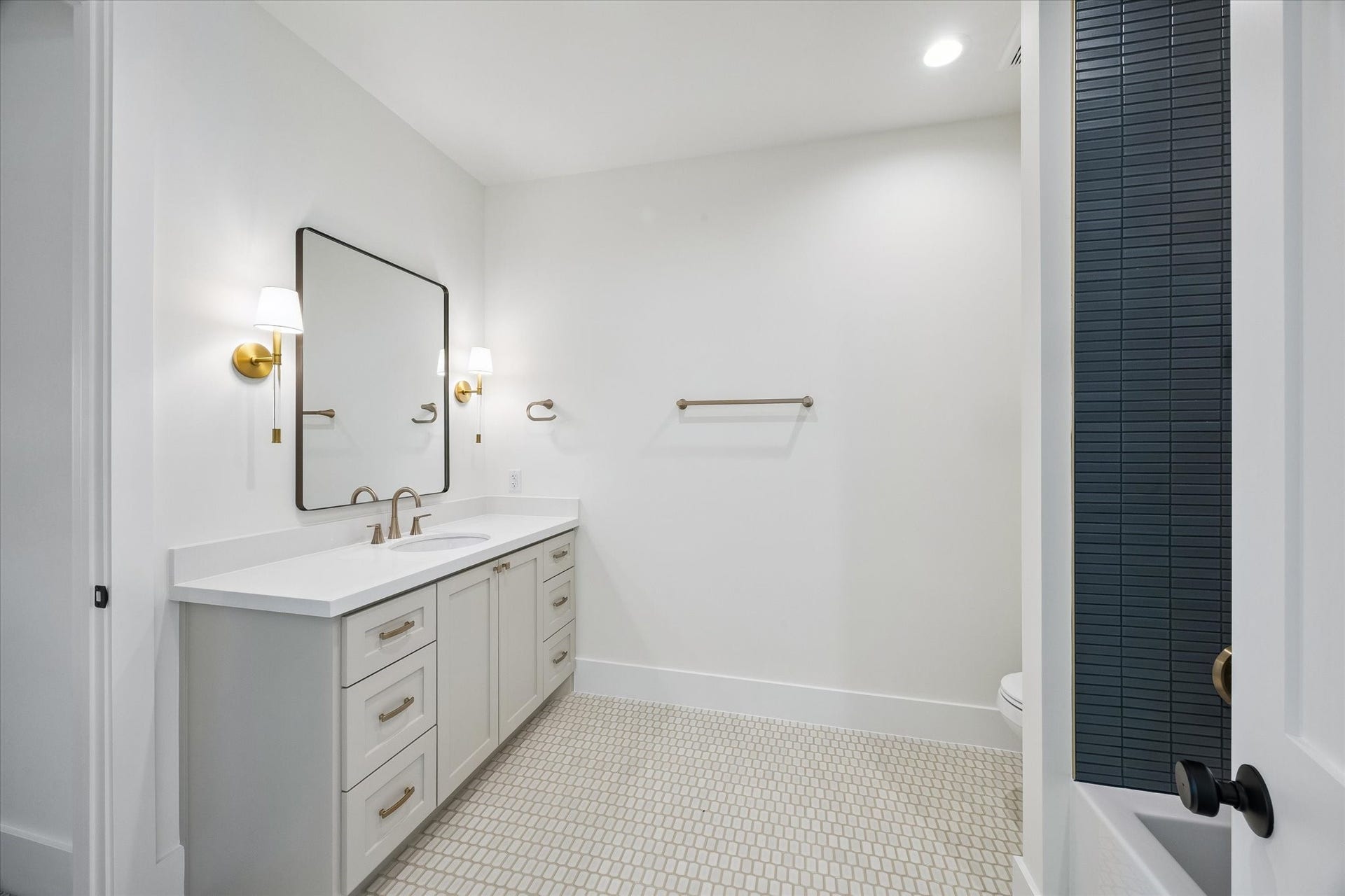 65 Shadow Creek Ridge Drive, Spring, TX 77389 Spa-inspired bathroom with quartz vanity, brass sconces, and striking floor-to-ceiling tiled shower.