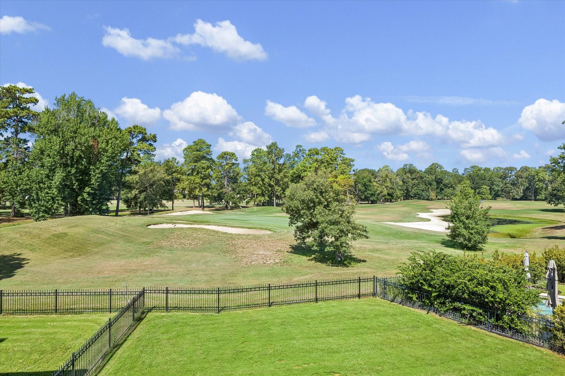 65 Shadow Creek Ridge Drive, Spring, TX 77389 Backyard with wrought-iron fencing opens to sweeping golf course fairway views and mature trees.