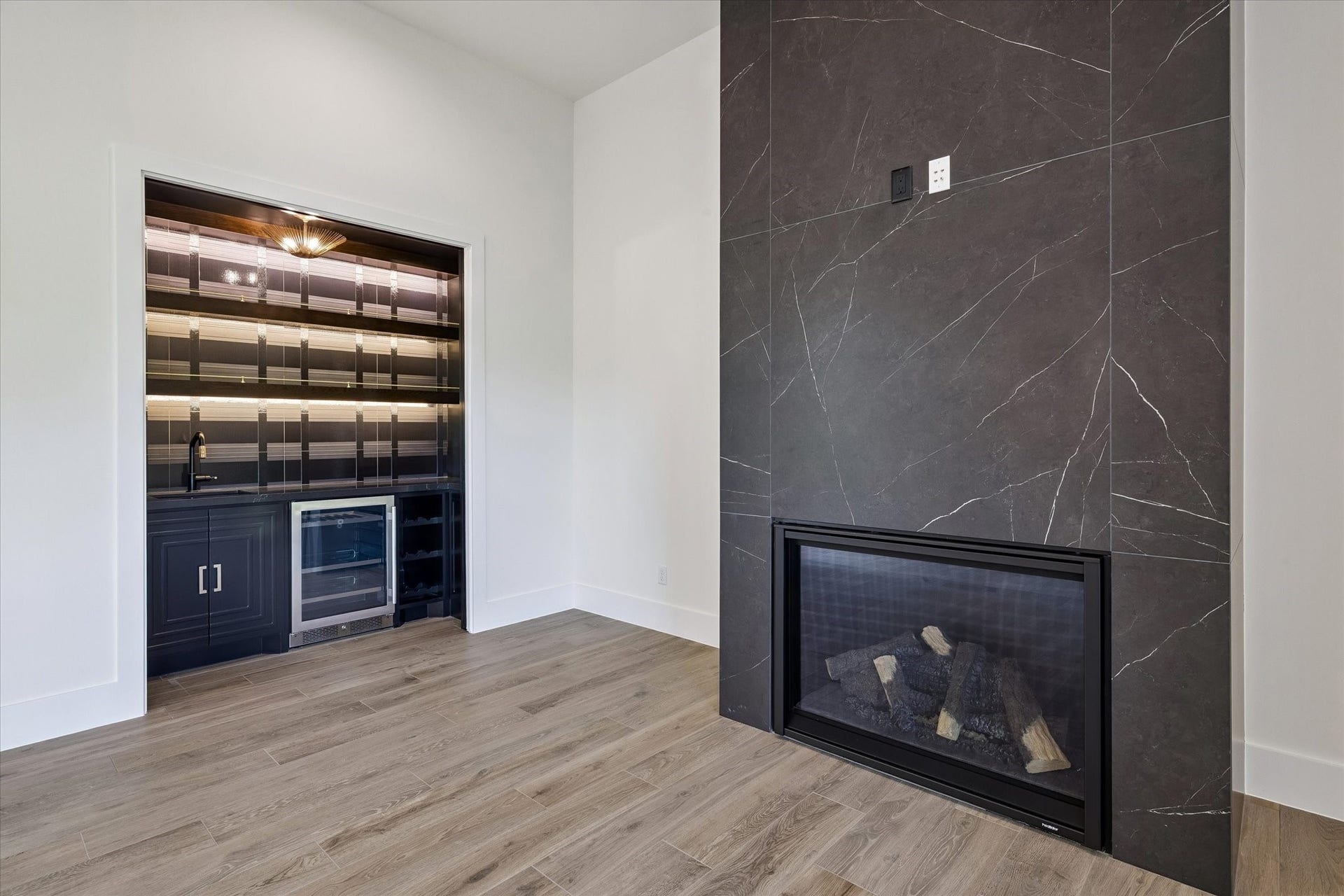 65 Shadow Creek Ridge Drive, Spring, TX 77389 Sleek porcelain-surround fireplace pairs with a built-in bar featuring cabinetry, lighting, and beverage fridge.
