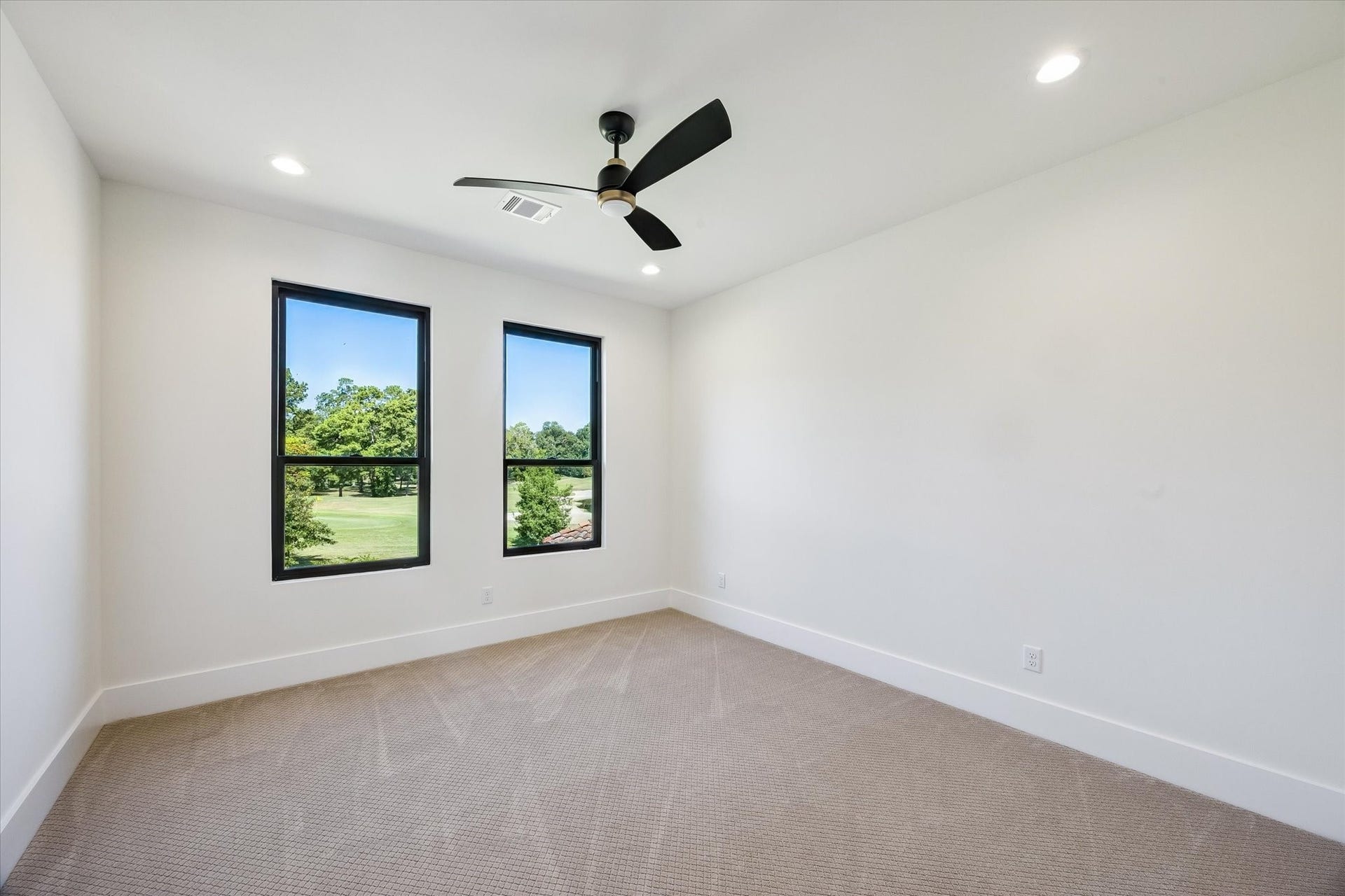 65 Shadow Creek Ridge Drive, Spring, TX 77389 Bright upstairs secondary bedroom with oversized windows, recessed lighting, and ceiling fan overlooking serene golf course views.