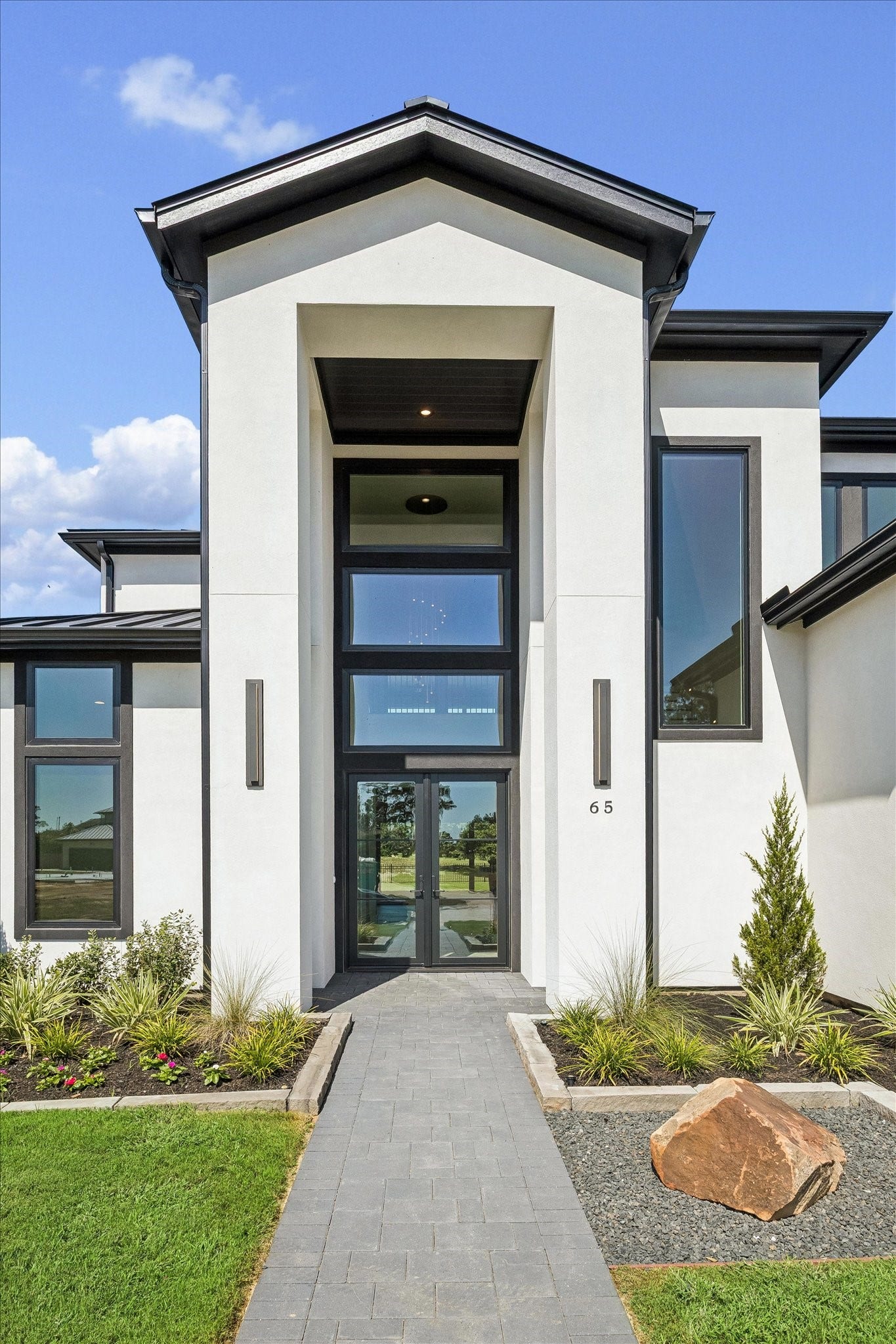 65 Shadow Creek Ridge Drive, Spring, TX 77389 Modern stucco exterior with soaring entry, black-framed windows, and a sleek glass front door.