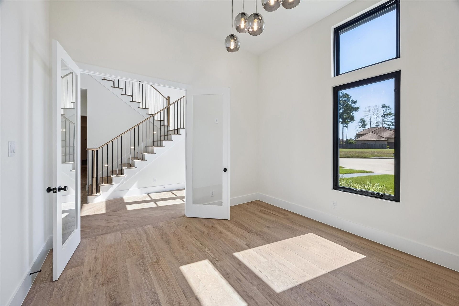 65 Shadow Creek Ridge Drive, Spring, TX 77389 A modern globe pendant adds just the right touch of drama, while crisp trim and clean lines keep the look timeless. Glass-paneled doors and an open view to the staircase create an airy, connected feel, perfect for a home office, reading room, or music space where natural light does most of the heavy lifting.