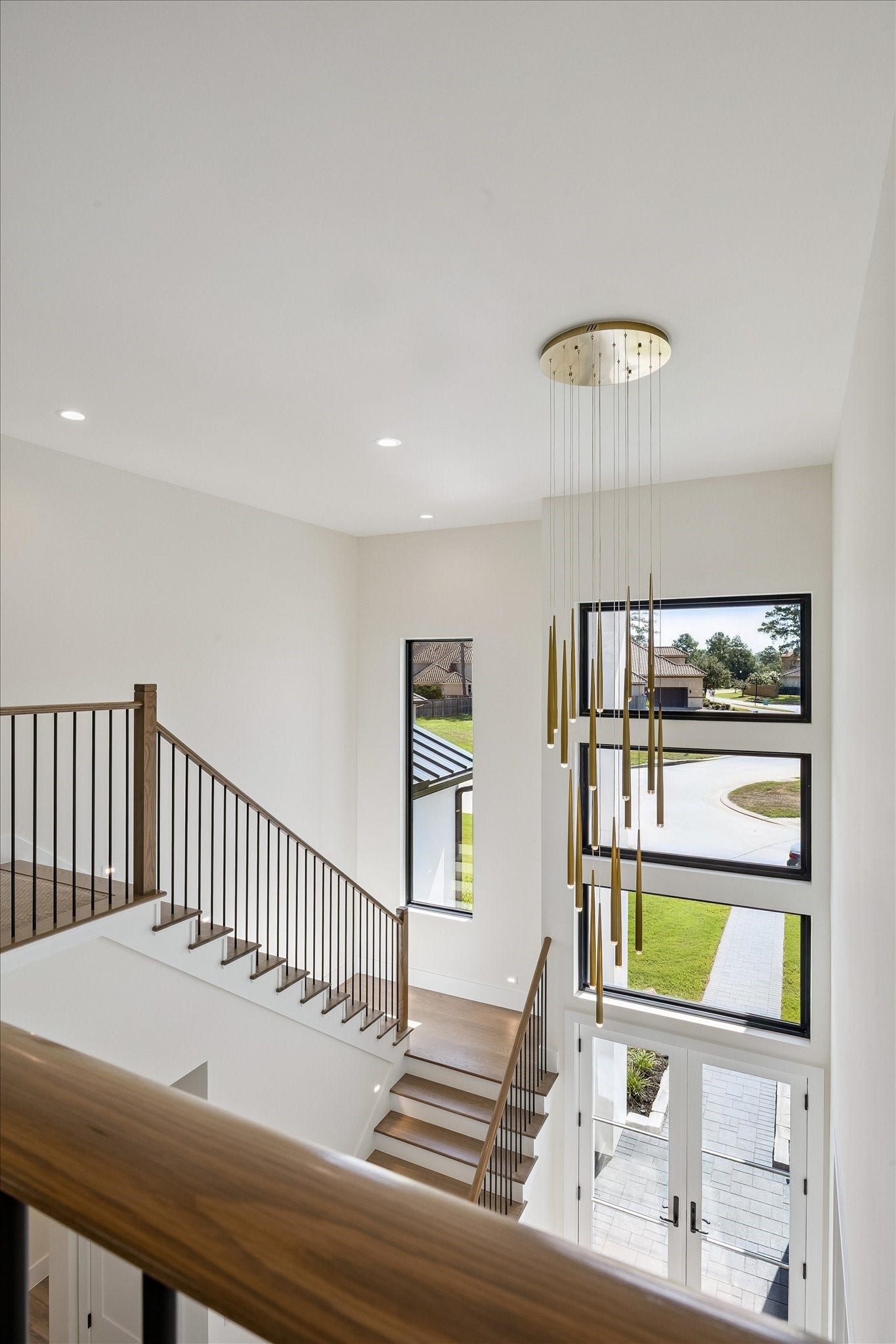 65 Shadow Creek Ridge Drive, Spring, TX 77389 Dramatic two-story foyer showcases a modern chandelier, floating stairs, and expansive picture windows.