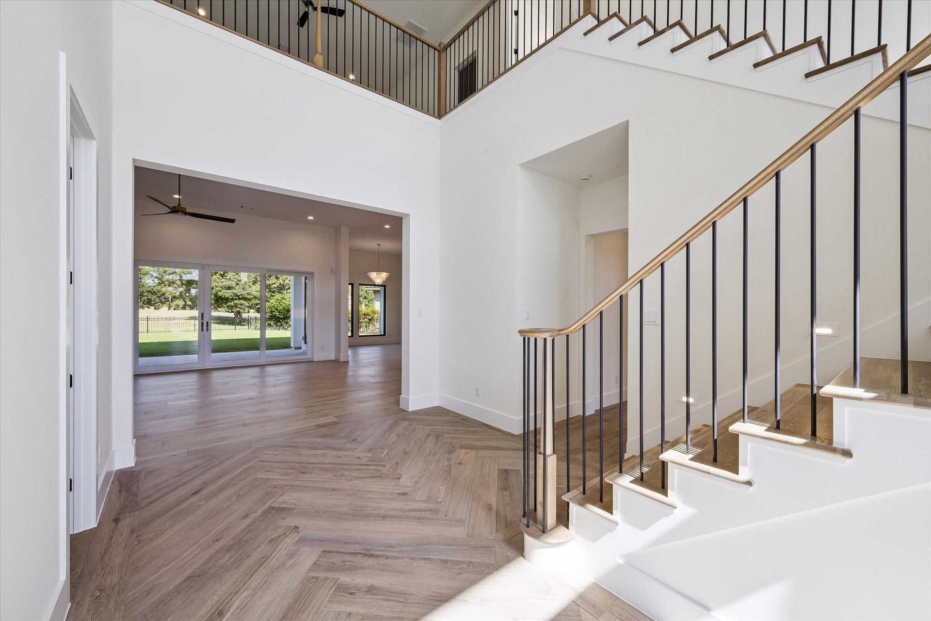 65 Shadow Creek Ridge Drive, Spring, TX 77389 Soaring ceilings, herringbone wood-style floors, and a sleek staircase frame sunlit open-concept living.