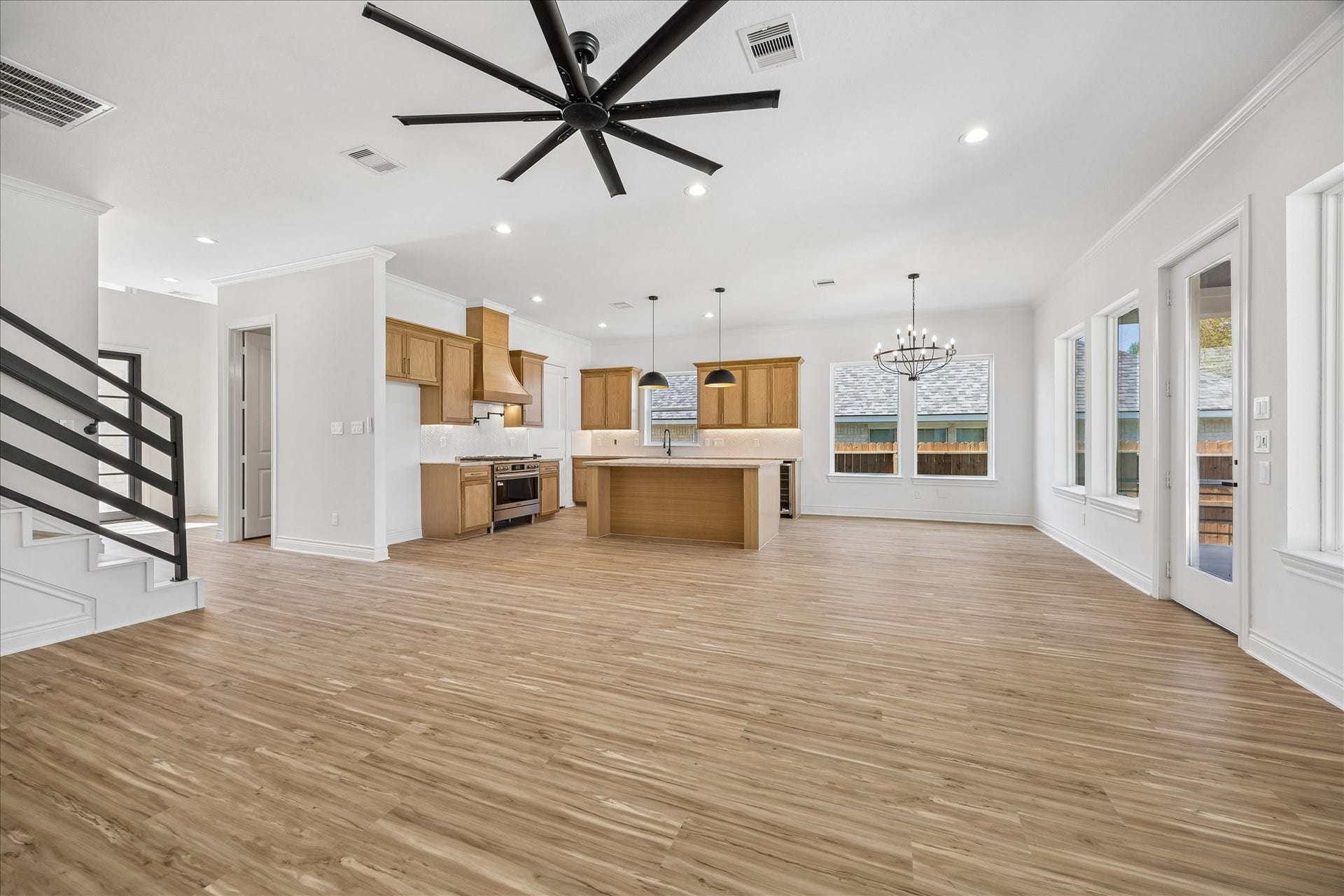 Spacious family room featuring a striking modern stair railing and an oversized ceiling fan, creating a stylish and comfortable space for relaxing and entertaining.