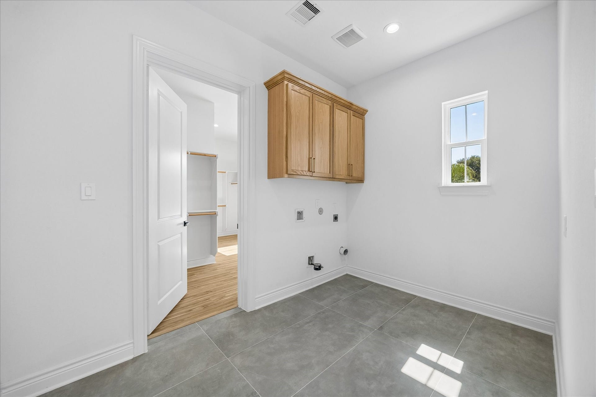 Well-appointed laundry room featuring ample cabinetry and convenient direct access to the spacious primary walk-in closet.