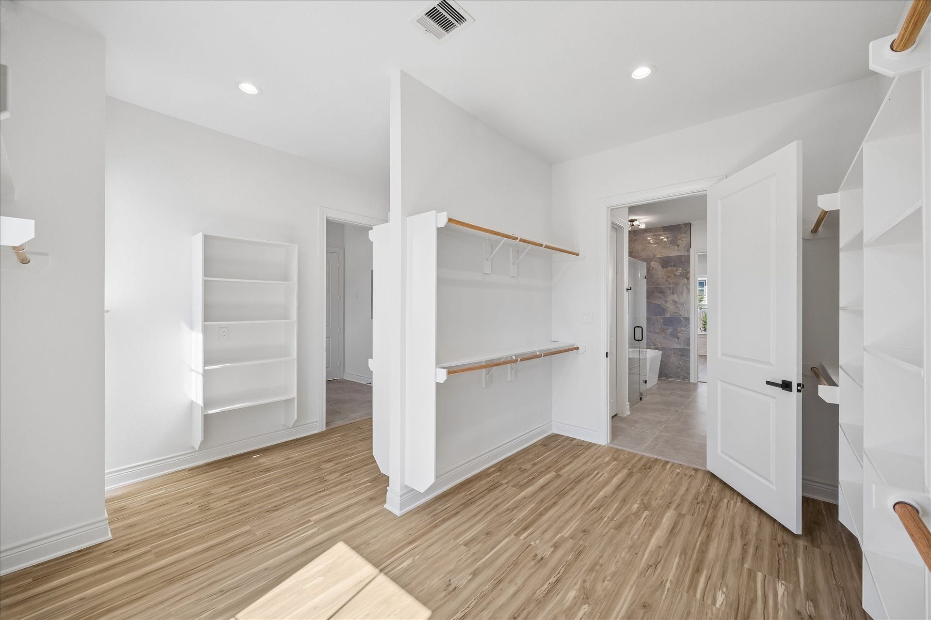 Expansive primary walk-in closet offering an abundance of space for clothing, shoes, and accessories, with convenient direct access to the laundry room.