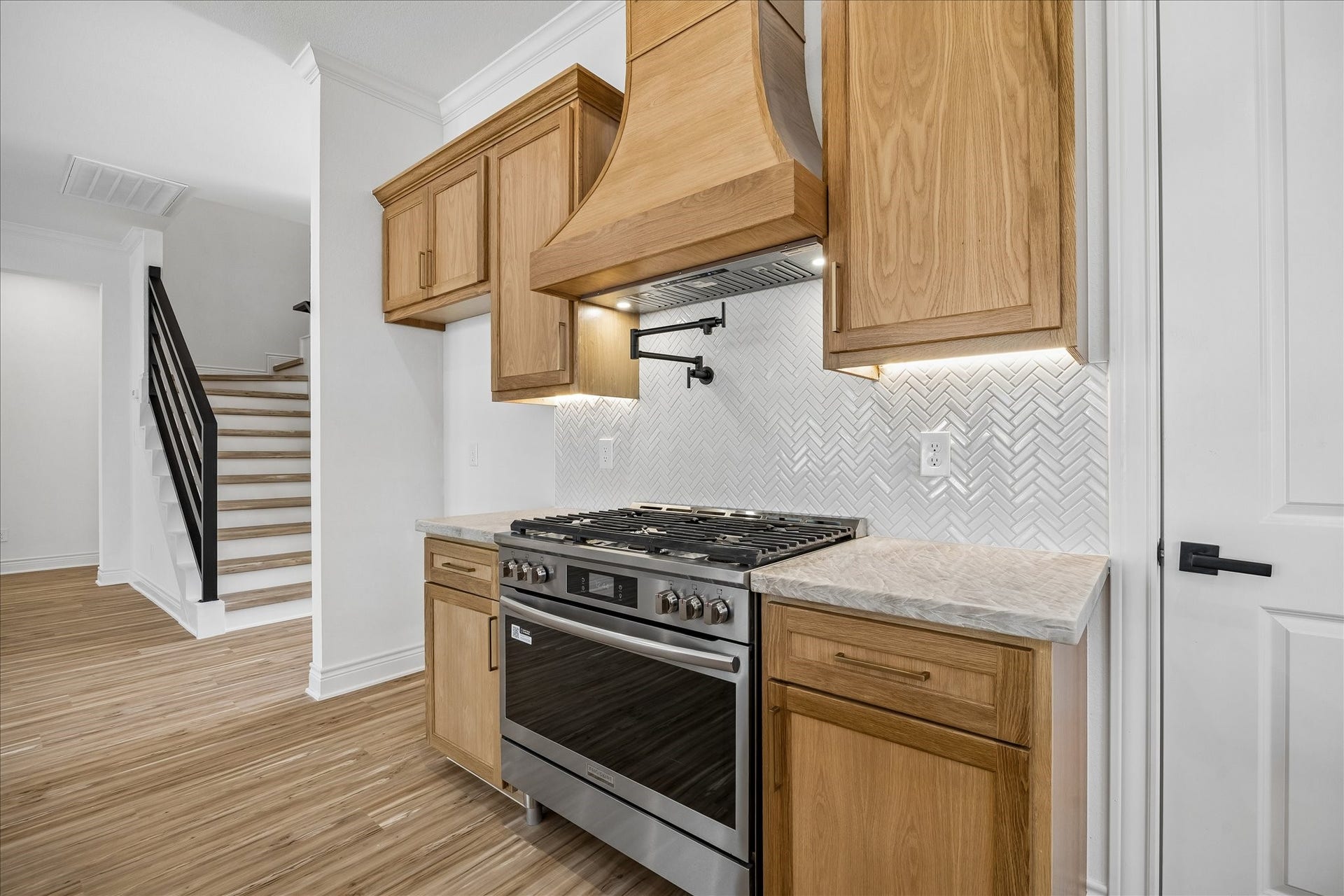 Custom-built white oak cabinetry featuring soft-close drawers for a touch of quality and convenience. The stainless steel 6 burner gas range and pot filler offer a modern elegance for everyday functionality.