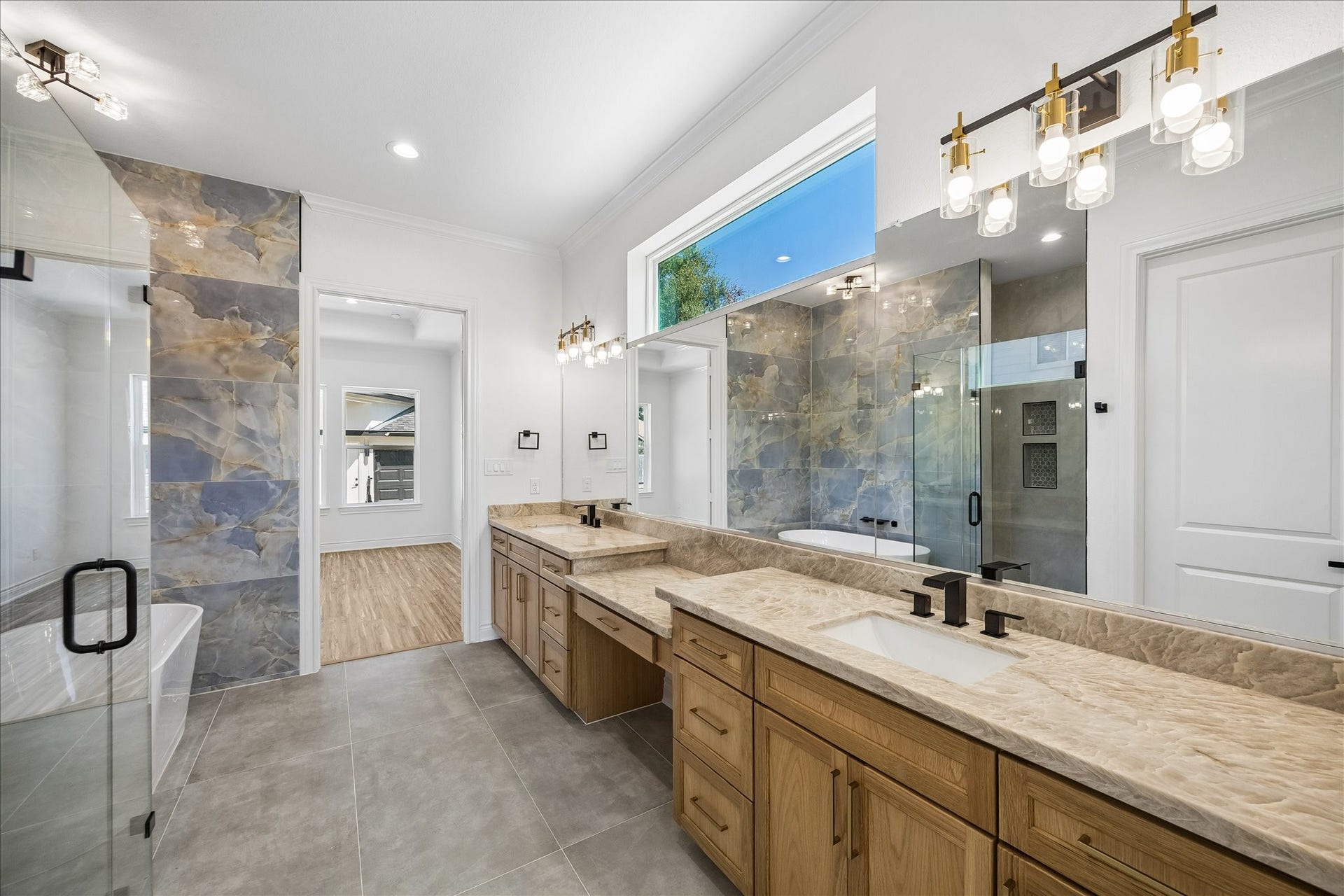 Luxurious primary bath featuring dual sink vanities including a dedicated makeup vanity with seating.