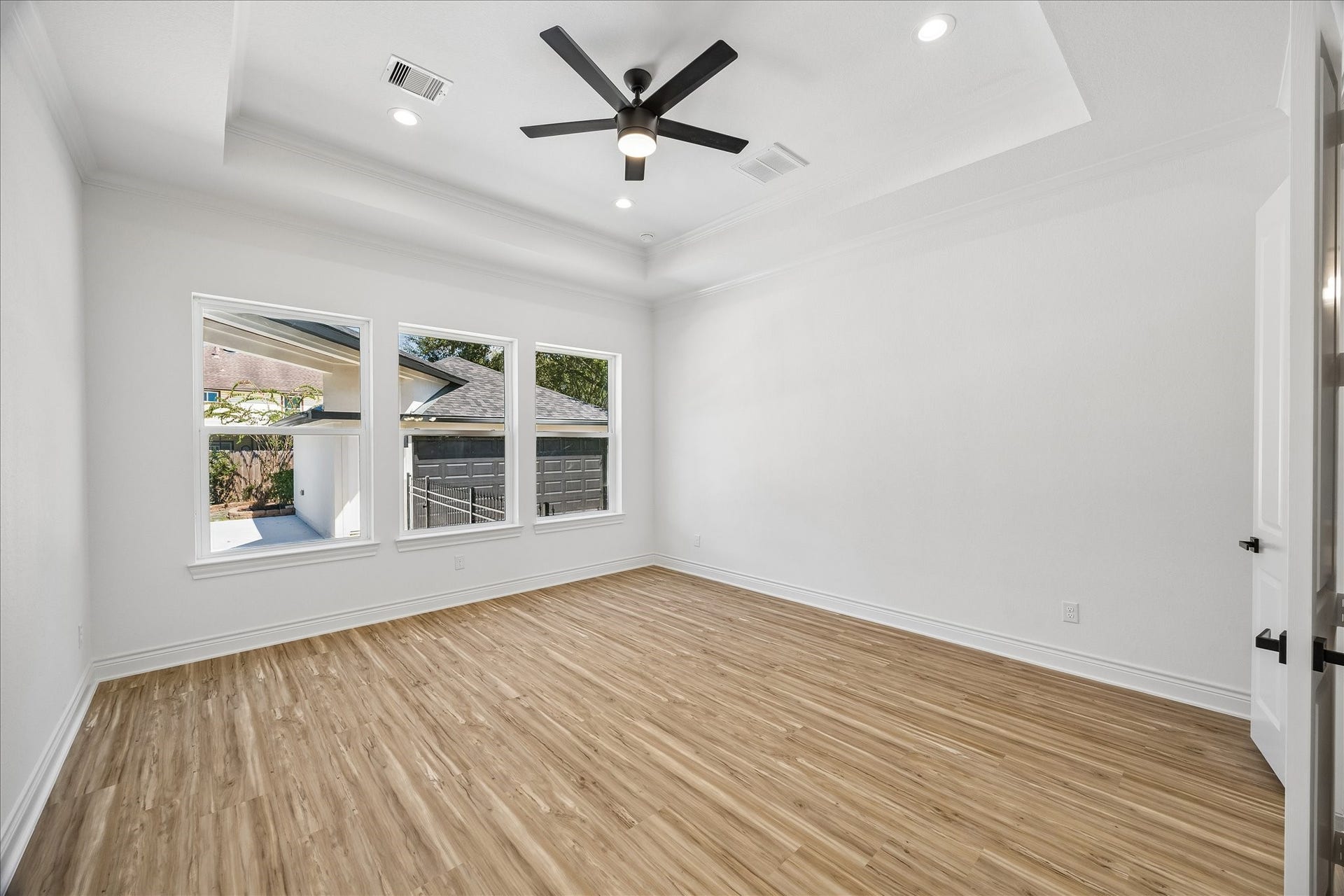 Spacious primary bedroom featuring elegant coffered ceilings and recessed lighting, with beautiful views that look out to the pool.