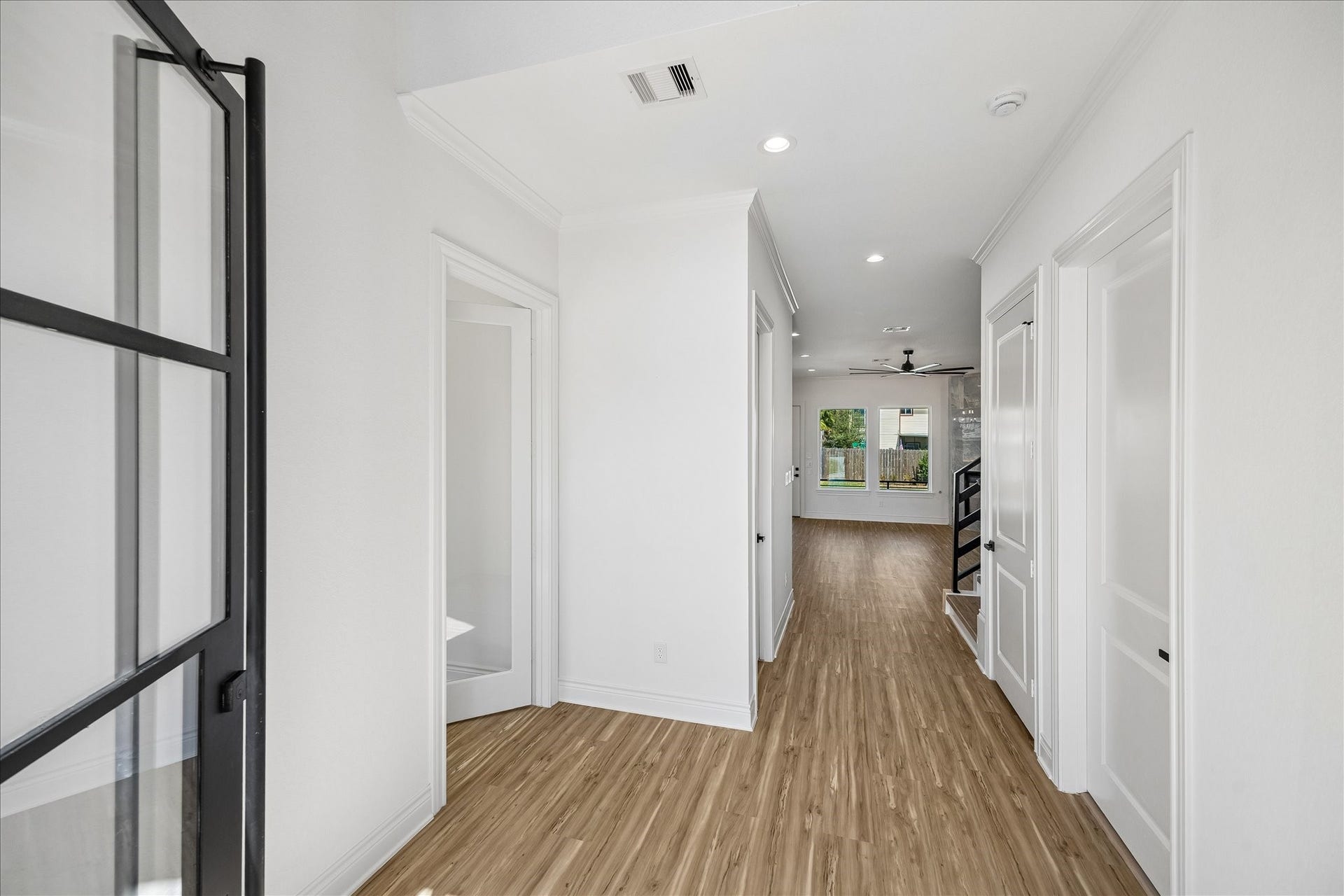 Welcoming entry featuring a modern black-framed glass front door, elegant trim work, and warm wood-look flooring that flows seamlessly into the open-concept living space.