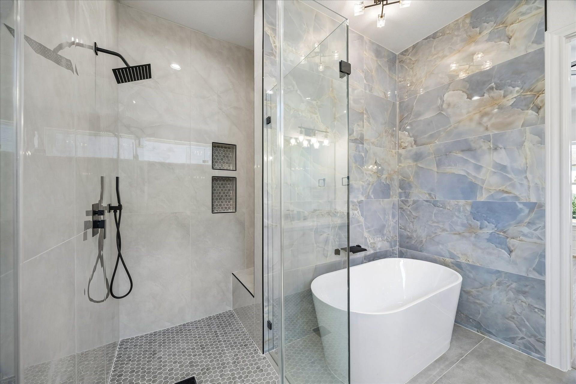 Spacious walk-in shower with a built-in seating area and recessed shampoo niches, complemented by a modern freestanding soaking tub.