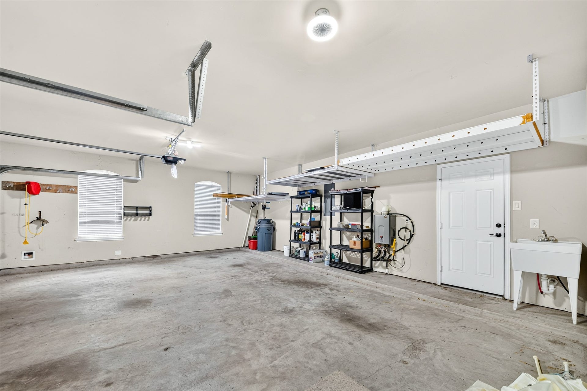 12218 Rampy Green Drive, Tomball, TX 77377 Spacious 3-car garage with ample storage solutions, featuring overhead racks, shelving units, and a convenient utility sink.