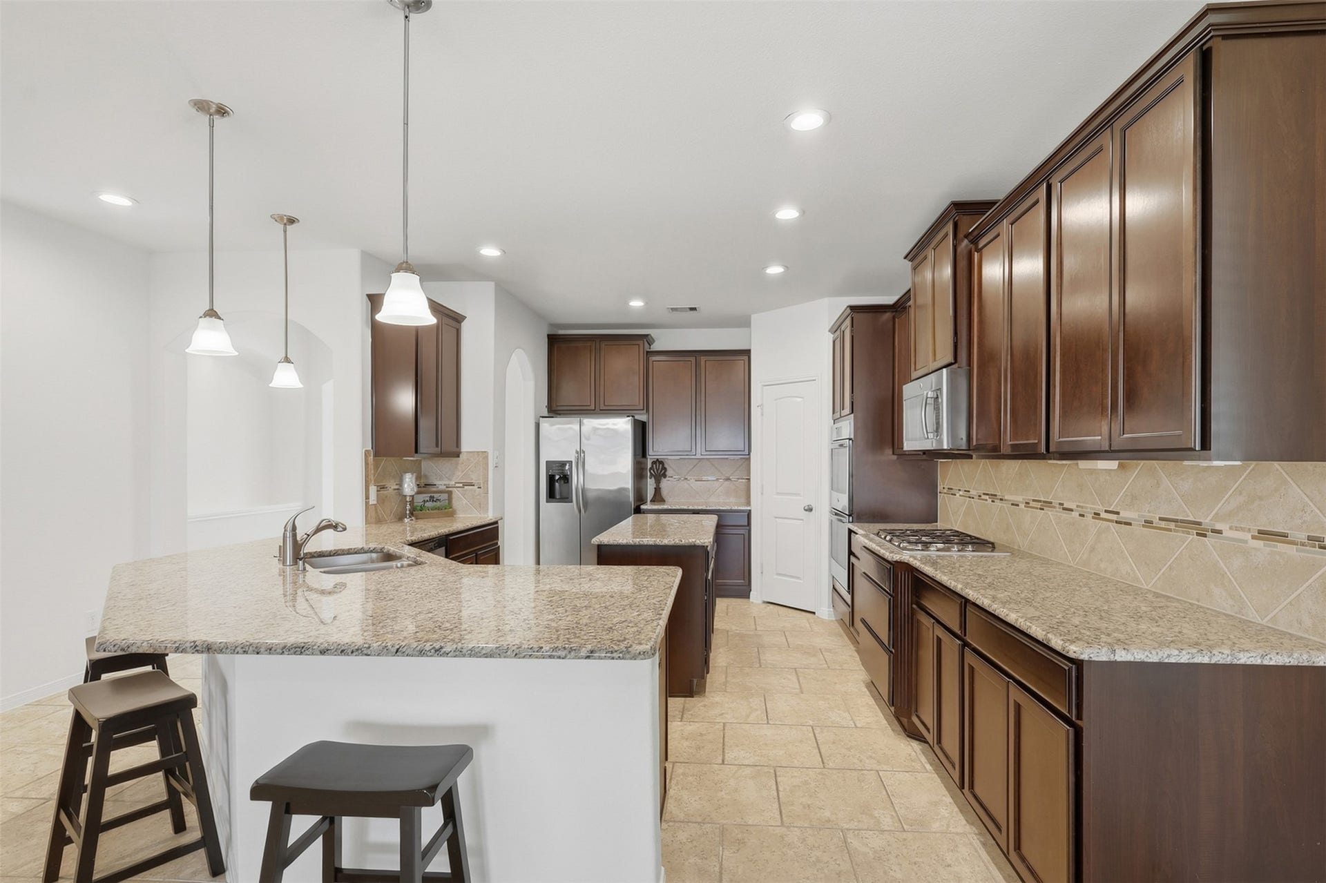 11723 Giovanni Lane, Richmond, TX 77406 Beautiful Kitchen with an Open, Welcoming Design! This fabulous kitchen offers abundant custom cabinetry, granite countertops, a large center island, breakfast bar seating, stainless steel appliances, and beautiful pendant lighting. The open layout keeps the kitchen connected to the dining and living areasperfect for busy family life and entertaining!