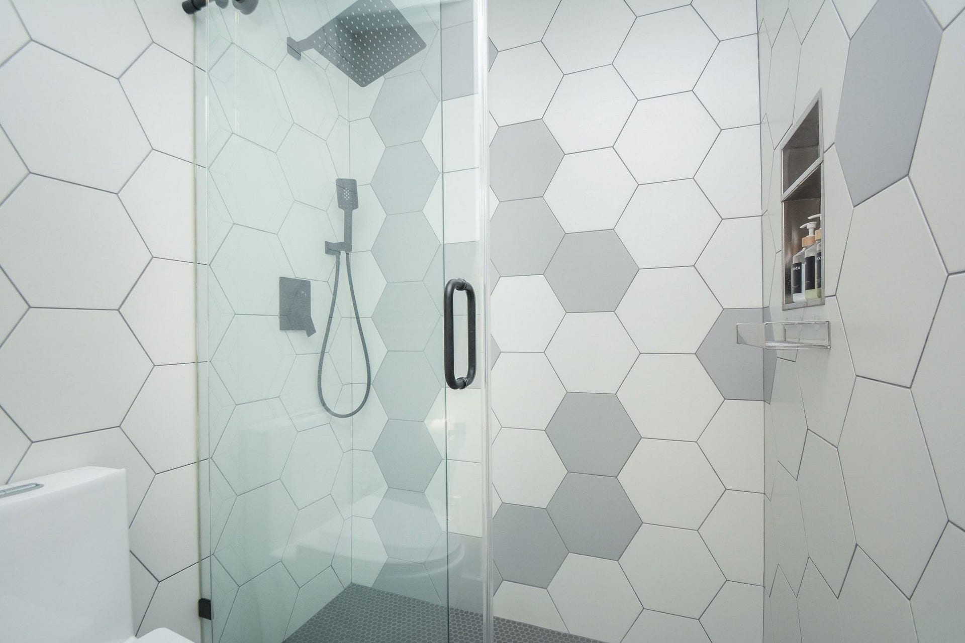 Beautifully remodeled walk-in shower featuring designer tile and modern black fixture