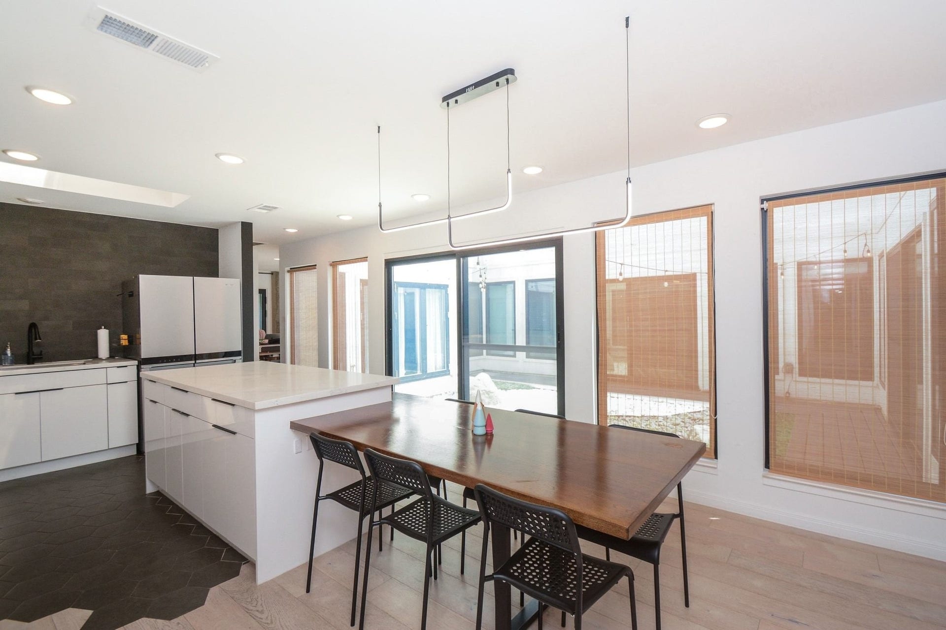 Spacious dining area with modern lighting, updated flooring, and views of the courtyard.