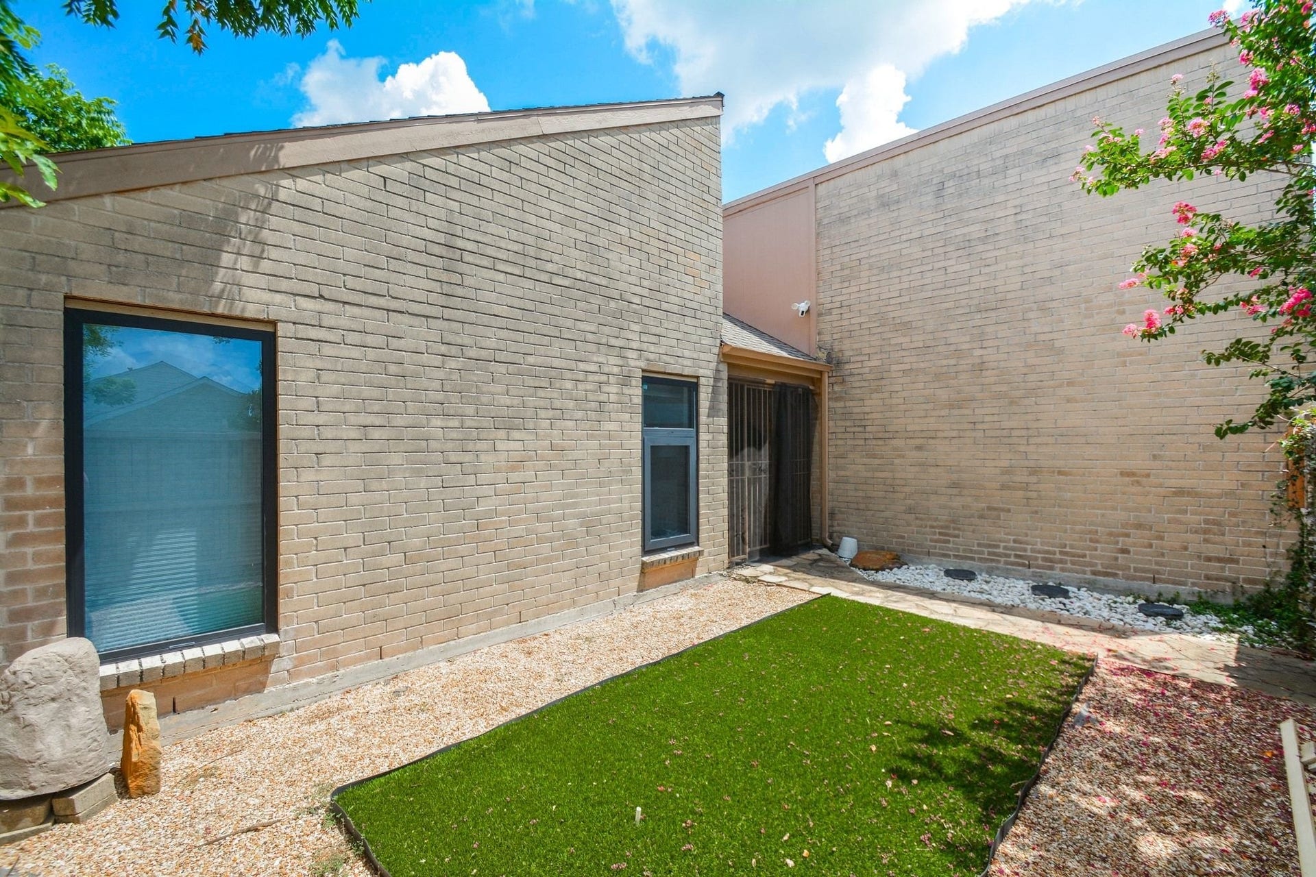 Updated exterior featuring modern siding, large windows, and landscaped side yard.