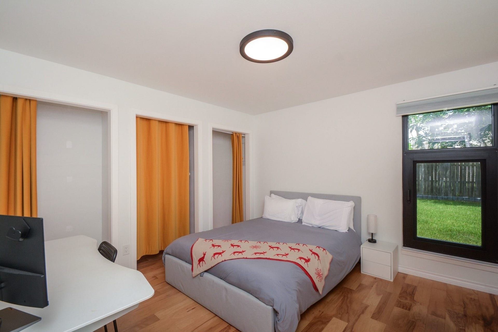 Well-appointed bedroom featuring updated flooring, modern ceiling fan, and ample natural light. 1ST BEDROOM