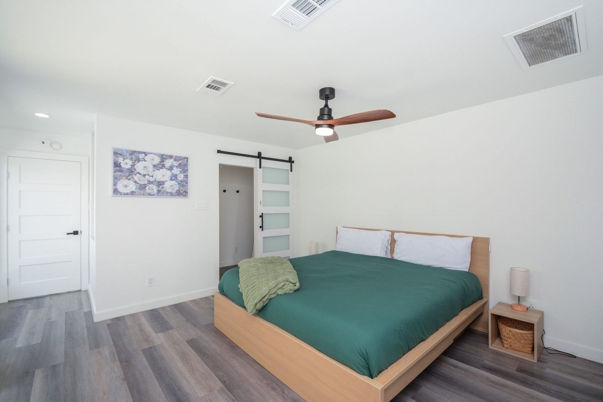 Bright primary bedroom featuring modern flooring, recessed lighting, and generous natural light.