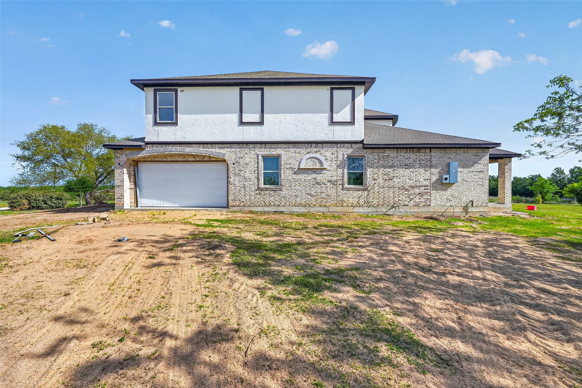 8023 Pool Hill Road, Fulshear, TX 77441 Side exterior view of Property 1 unfinished residence featuring attached garage, and surrounding open land.