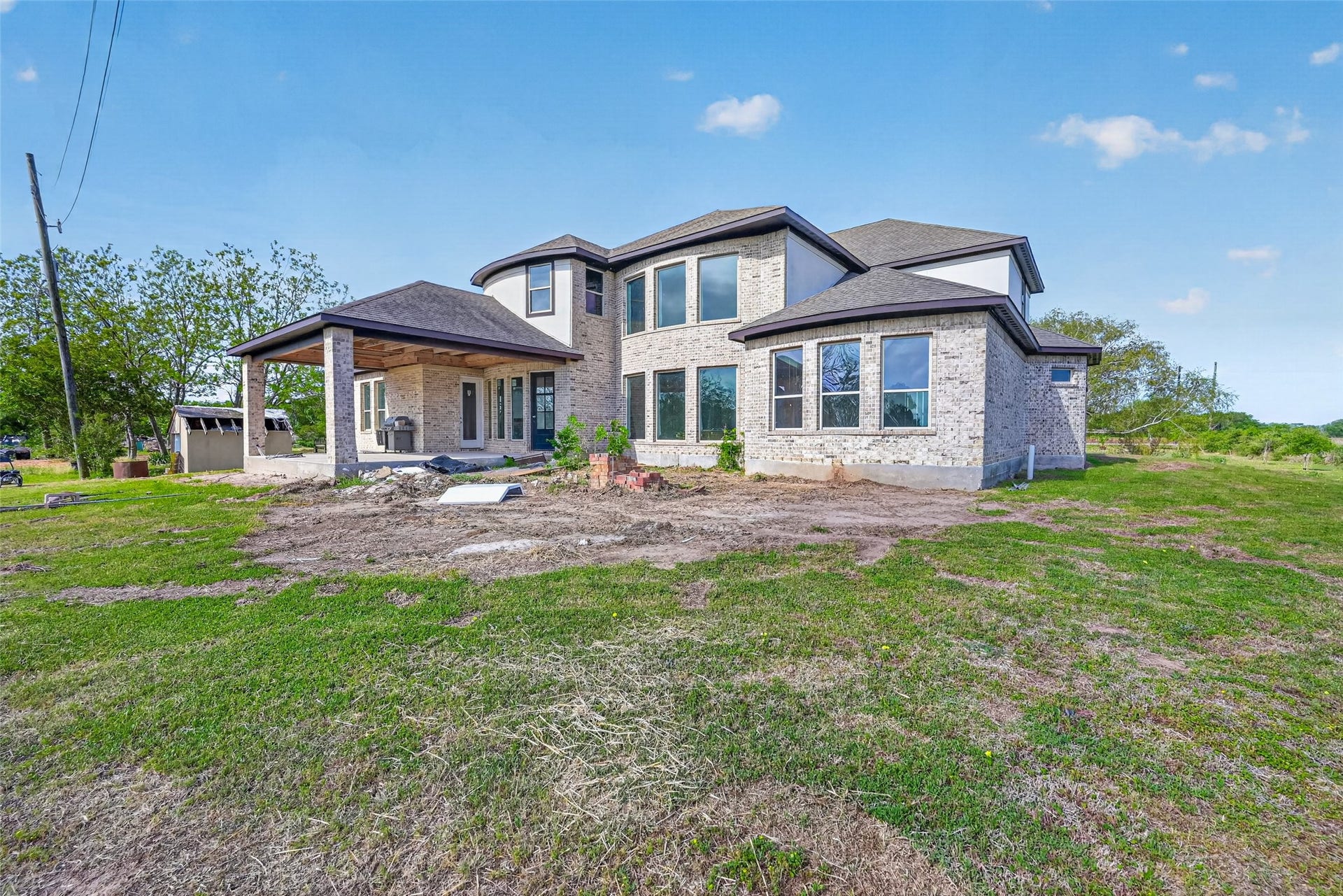 8023 Pool Hill Road, Fulshear, TX 77441 Rear exterior of Property 1 unfinished residence with covered patio, open backyard, and view of the existing lawn.