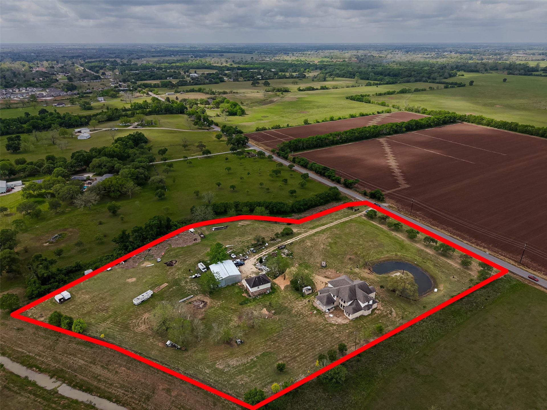 8023 Pool Hill Road, Fulshear, TX 77441 Aerial view of the property with outlined boundaries, multiple improvements, pond, and surrounding rural landscape.