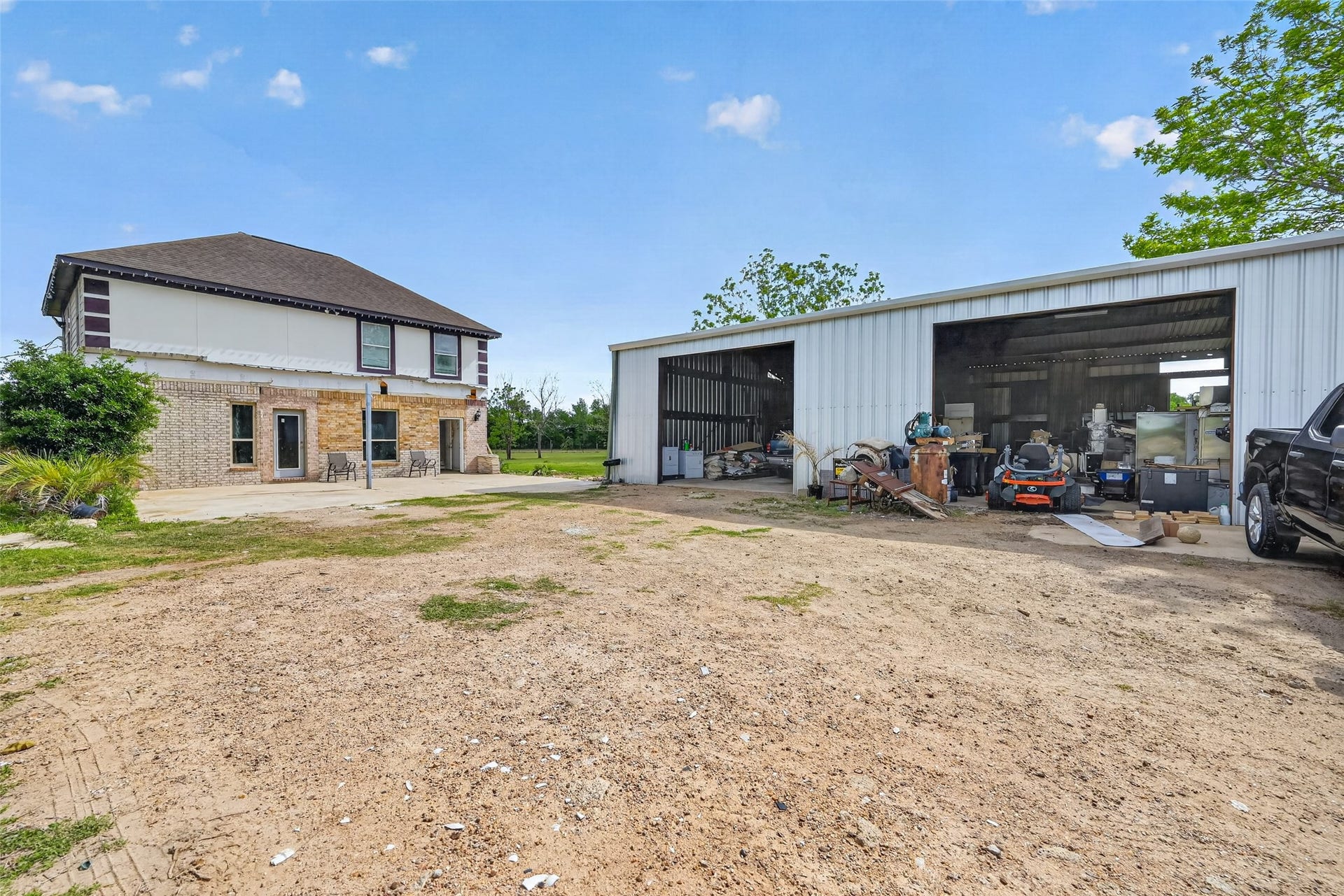 8023 Pool Hill Road, Fulshear, TX 77441 Exterior view showing Property 2 semi-finished residence and Property 3 metal outbuilding with open yard space.