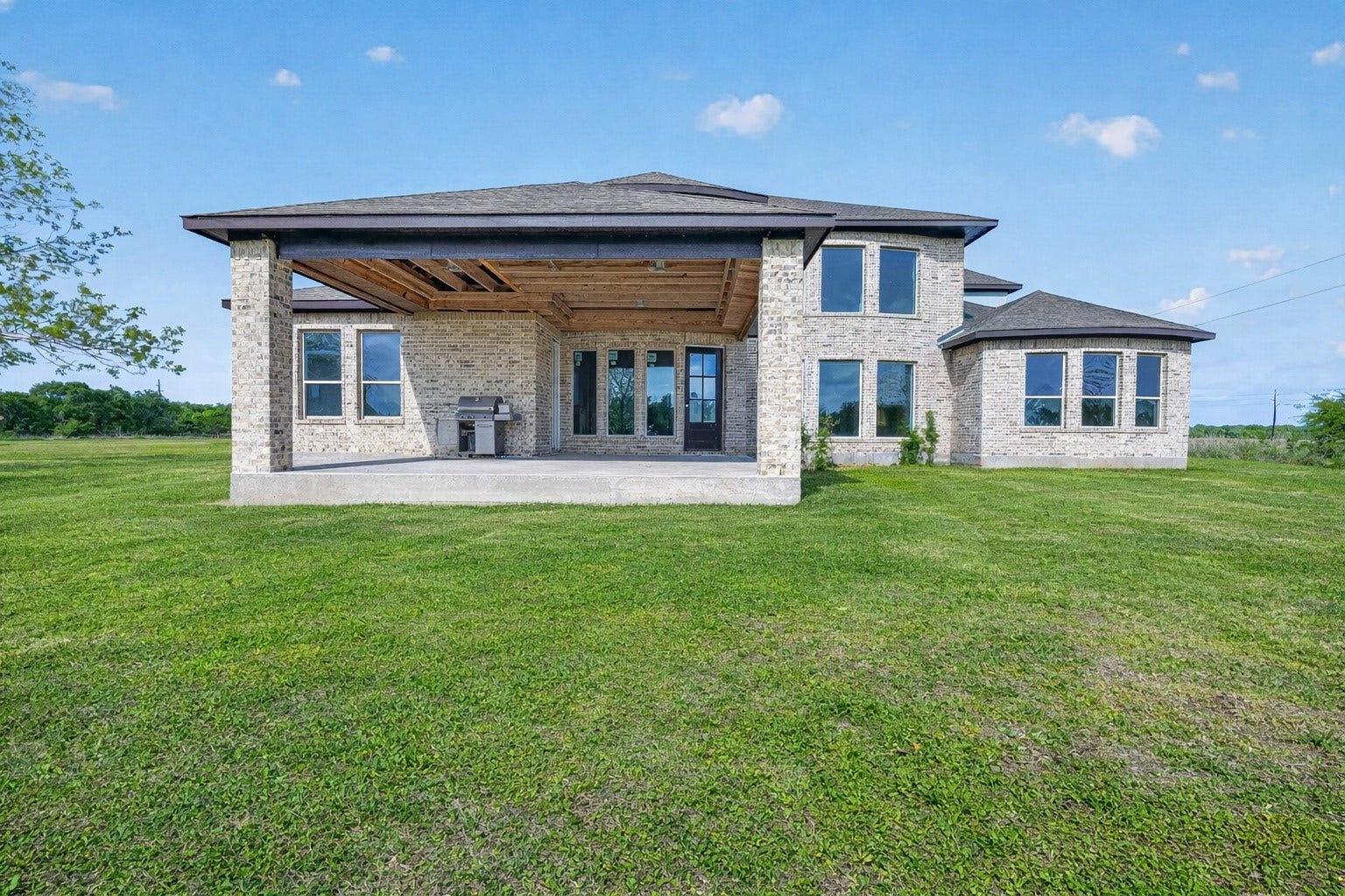 8023 Pool Hill Road, Fulshear, TX 77441 Rear exterior property 1 unfinished residence, with covered patio, open backyard, and virtually enhanced lawn.