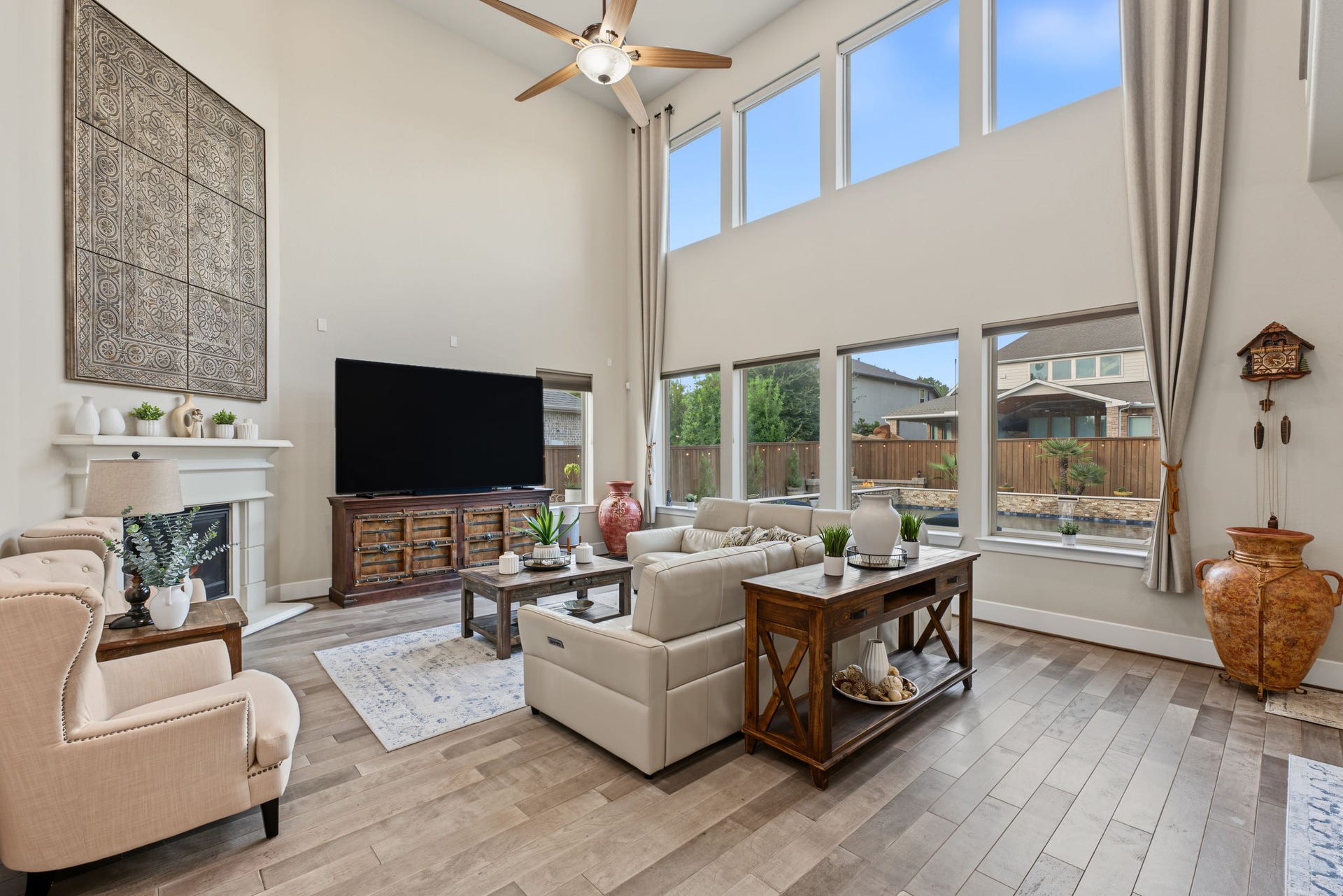 Beautifully appointed family room featuring a wall of windows overlooking the backyard, high ceilings, and an inviting atmosphere. Living area also features a cozy fireplace, soaring ceilings, and an open layout perfect for entertaining.