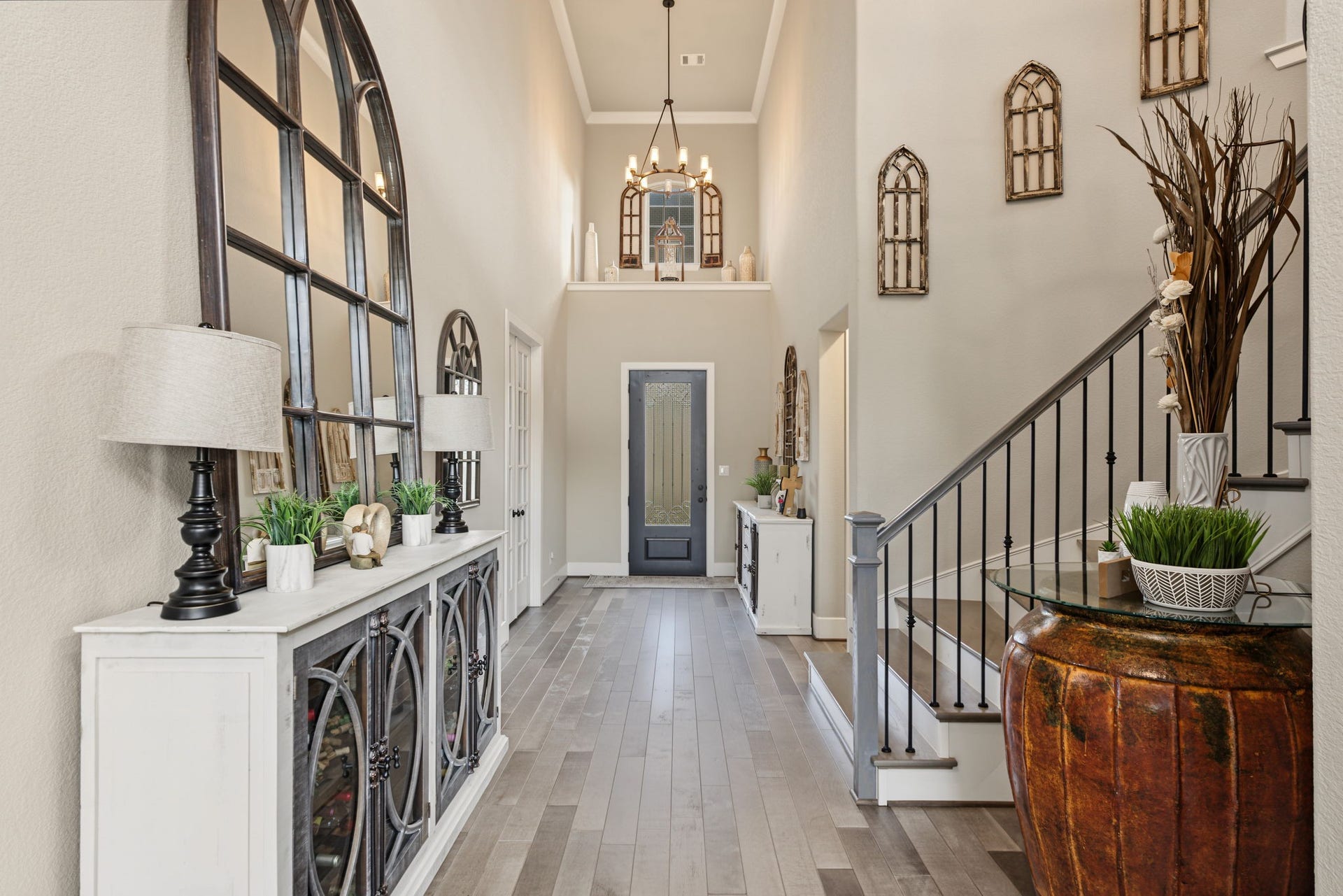 Another beautiful view of the impressive entryway featuring a striking staircase, decorative iron railing, and elegant chandelier.