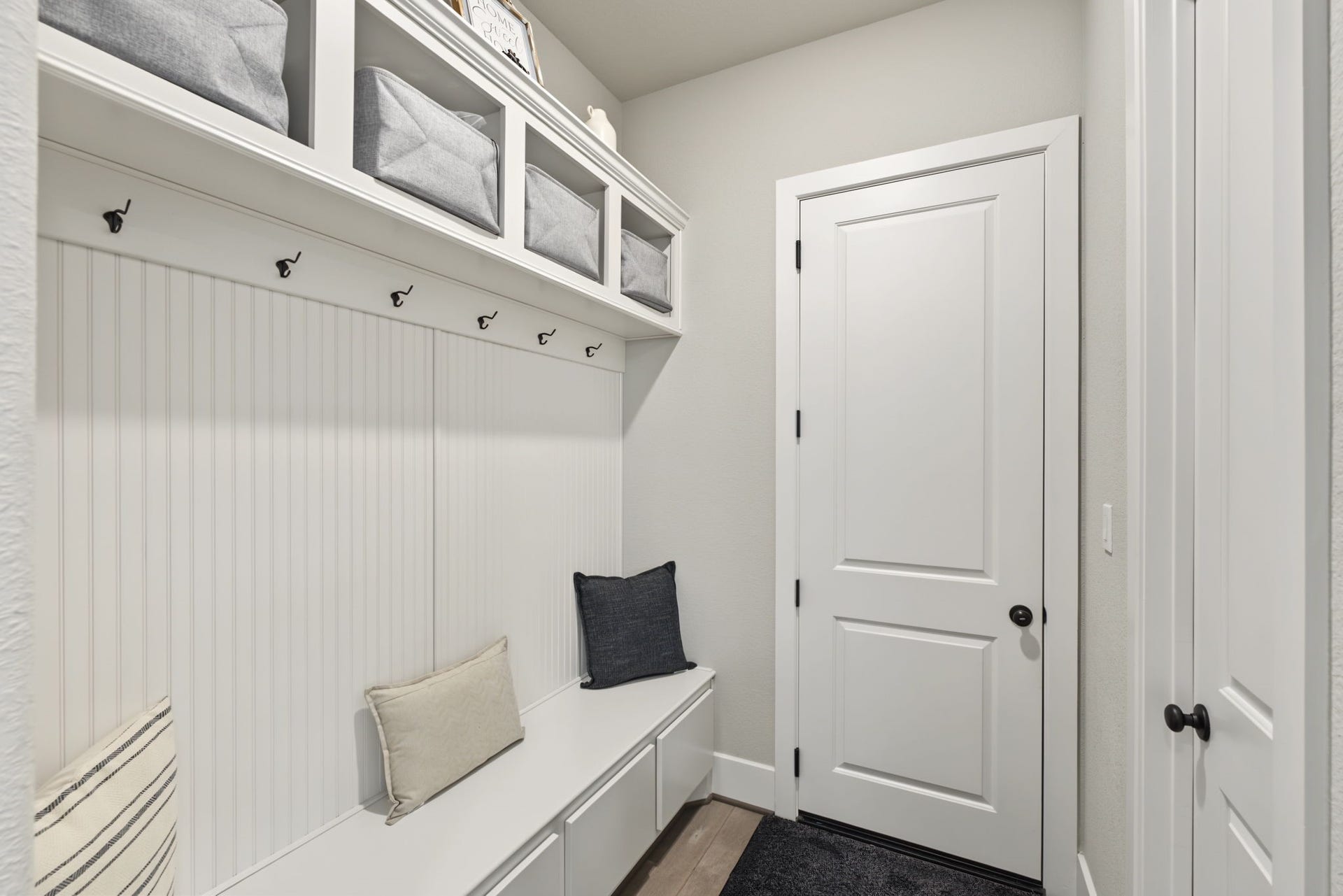 Convenient mudroom featuring built-in cabinetry, storage cubbies, hooks, and a bench to keep everyday essentials organized.