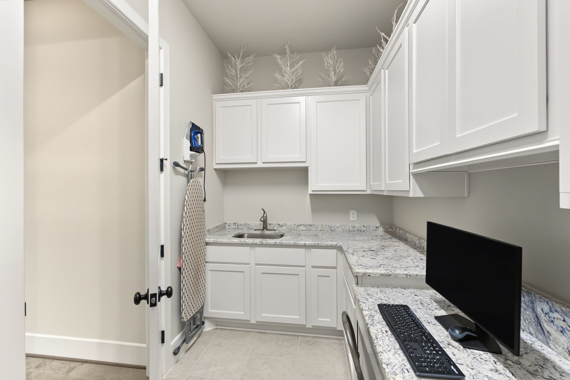 Another view of the oversized laundry room highlighting extensive storage, counter space, and a utility sink.